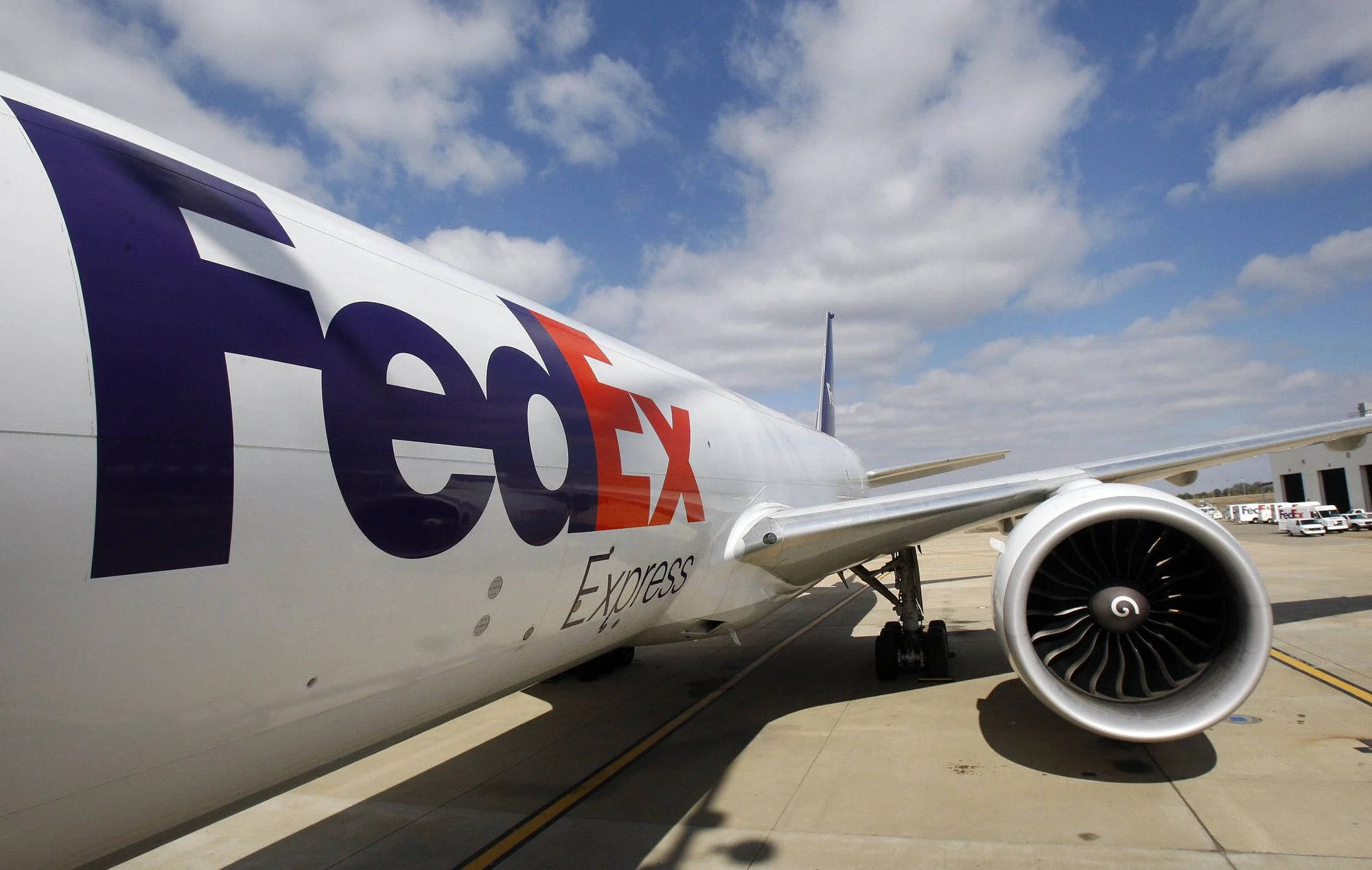 聯邦快遞 桌布 壁紙 — 一架FedEx Express貨機停泊在陽光普照的停機坪上，藍天白雲。