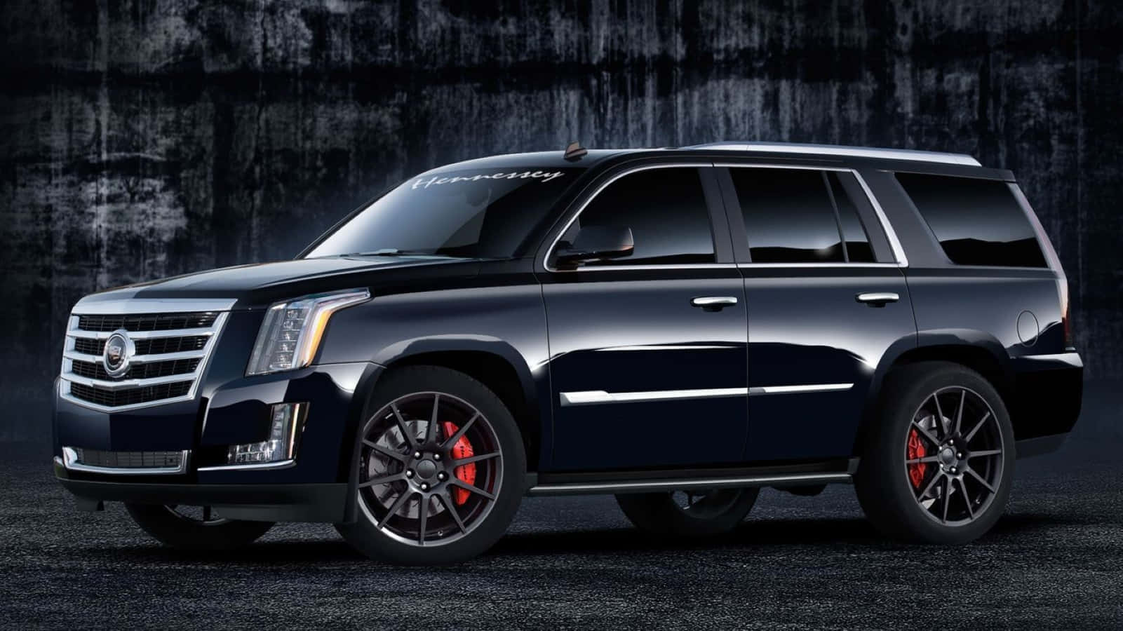 Cadillac Escalade 桌布 壁紙 — 一架Hennessey改裝的黑色Cadillac Escalade，配備紅色制動卡鉗，停在深色紋理牆前。