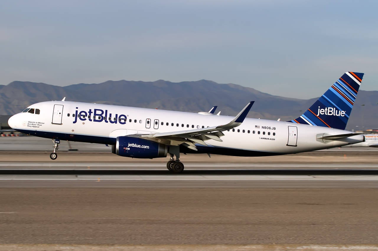 飛機 桌布 壁紙 — 一架JetBlue空中巴士A320在晴朗天空下的跑道上滑行，遠處有山。