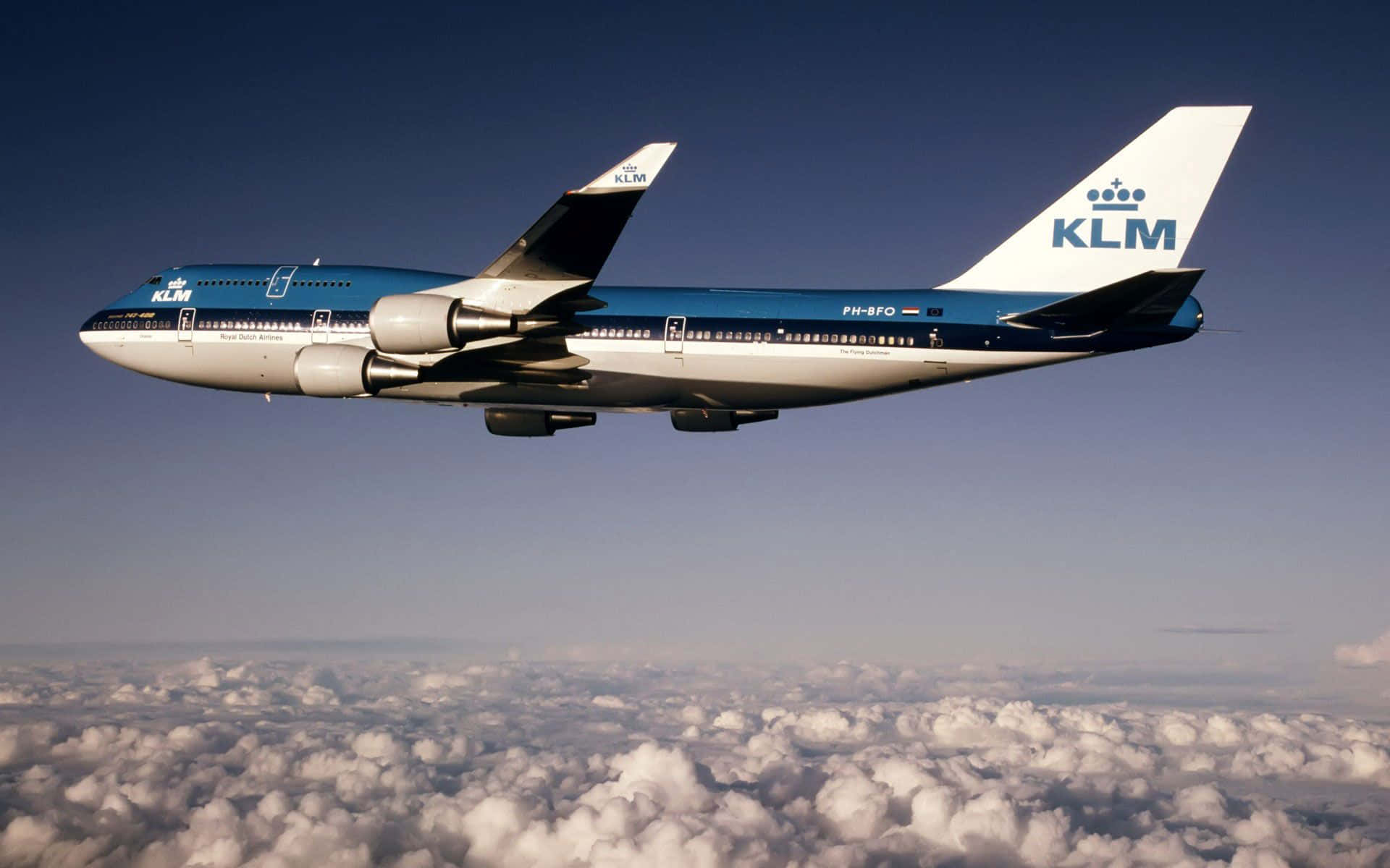 747 Airplane 桌布 壁紙 — 一架KLM波音747在晴朗藍天下，優雅地翱翔於大片蓬鬆白雲之上。