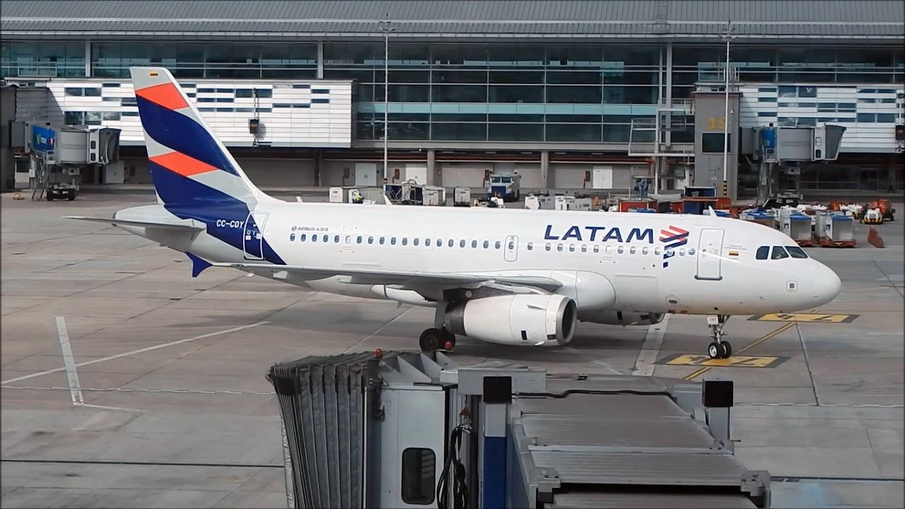 Airport 桌布 壁紙 — 一架LATAM航空的空中巴士A320停泊在機場閘口，並在現代化航廈下連接了空橋。