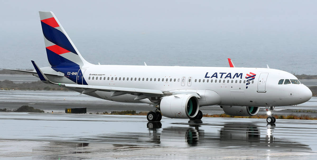 Airport 桌布 壁紙 — 一架LATAM航空的空中巴士A320停在濕滑的停機坪上，在灰色天空的映襯下，反射出其流線型的白色機身和色彩繽紛的尾翼。