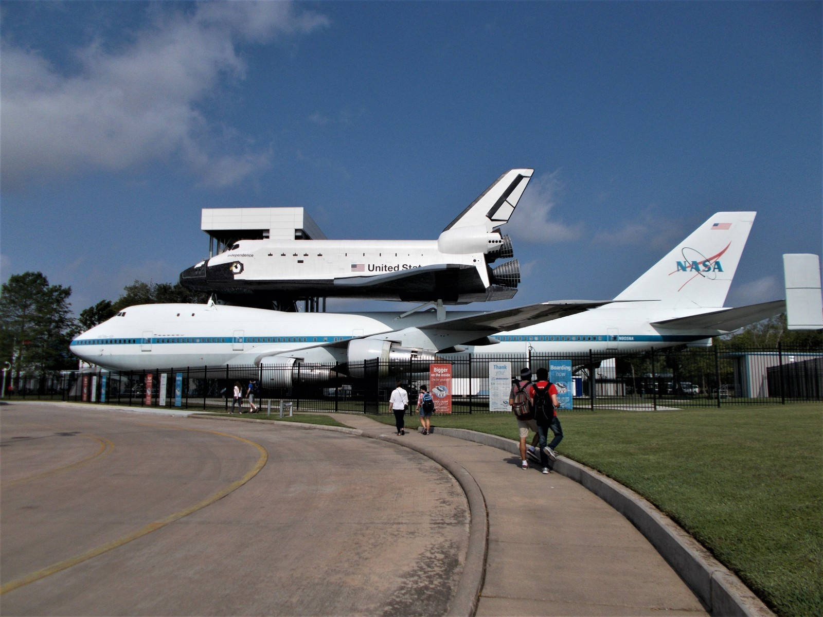 德州 桌布 壁紙 — 一架NASA太空梭安裝在改裝的波音747飛機上，在戶外展出，背景是晴朗的藍天和零星的白雲。
