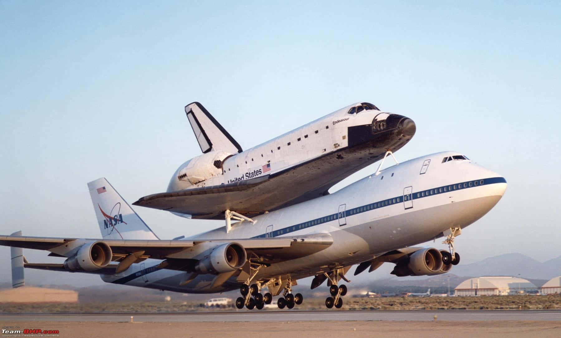 Jumbo Jets 桌布 壁紙 — 一架NASA太空梭安裝在波音747飛機上方，在晴朗藍天下的跑道上。