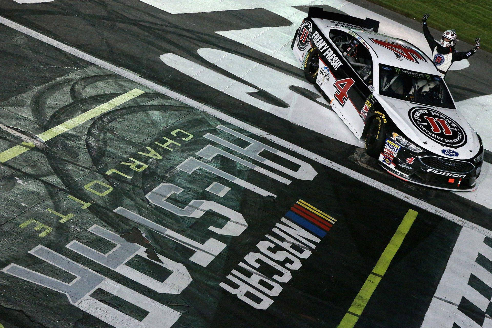 Kevin Harvick 桌布 壁紙 — 一架NASCAR賽車與車手在夜間濕滑賽道上於終點旗前慶祝勝利。