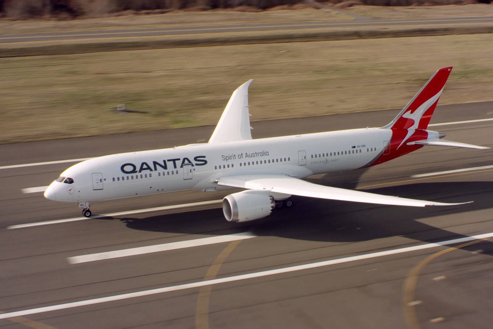 飛機 桌布 壁紙 — 一架Qantas Spirit of Australia波音787從跑道起飛，背景是模糊的草地。