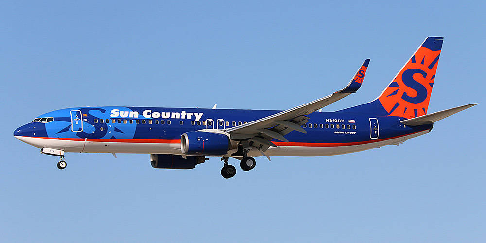 飛機 桌布 壁紙 — 一架Sun Country Airlines的波音737，以鮮豔的藍色和橙色塗裝，在晴朗的藍天中翱翔，起落架已放下。