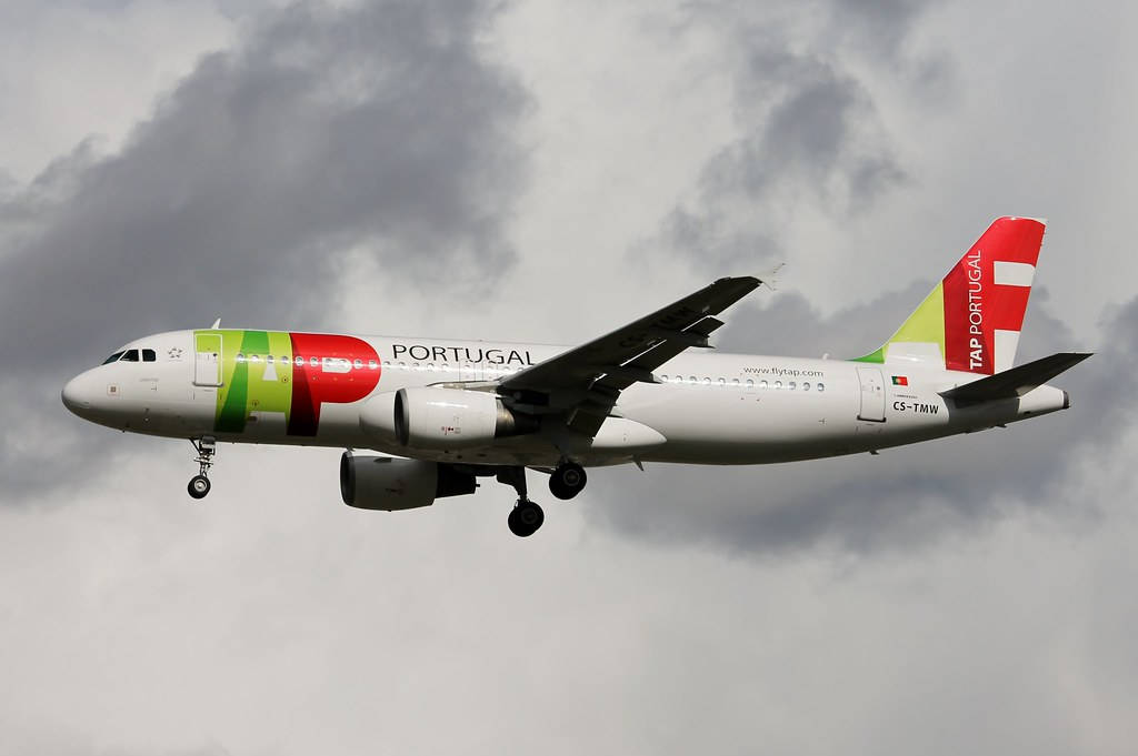  壁紙 — 一架TAP葡萄牙航空的空中巴士A320放下起落架，在戲劇性的多雲天空中翱翔。
