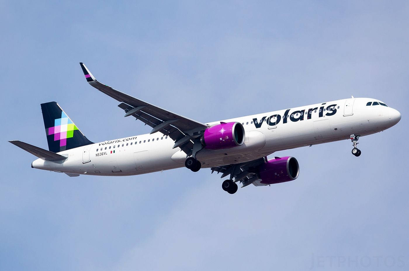 transportation 桌布 壁紙 — 一架Volaris空中巴士A320，配備紫色引擎和色彩繽紛的尾翼，在白天晴朗的藍天下飛行。
