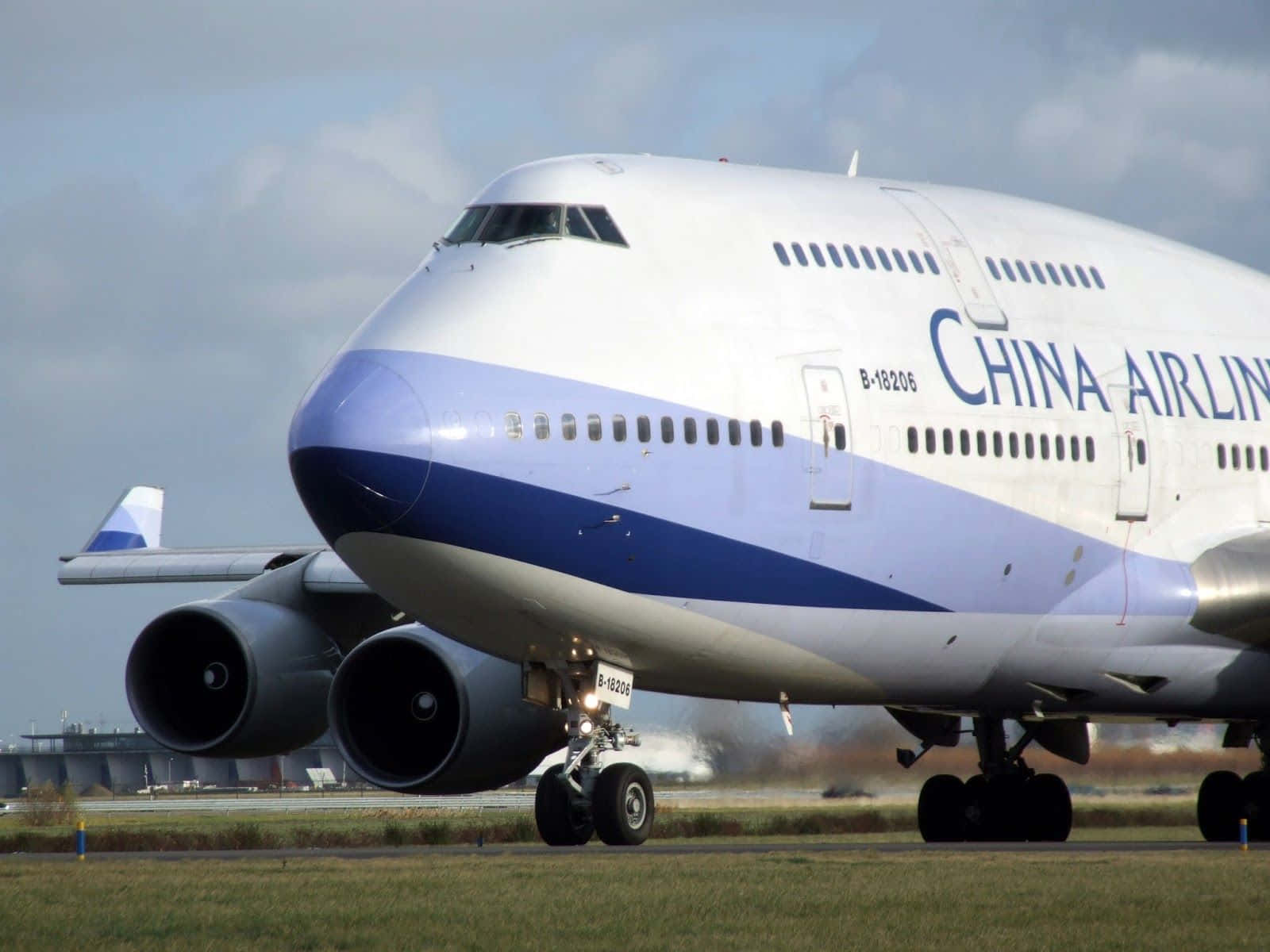 747 Airplane 桌布 壁紙 — 一架中華航空波音747在跑道上滑行，背景是草地和陰天。
