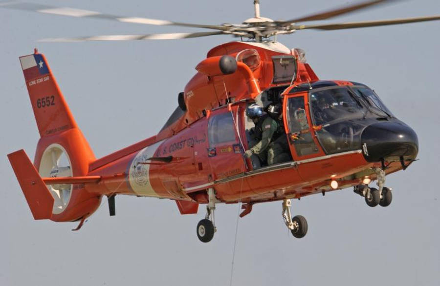 helicopter 4K 桌布 壁紙 — 一架亮橙色的美國海岸警衛隊直升機，機組人員清晰可見，在蒼白的天空中盤旋。