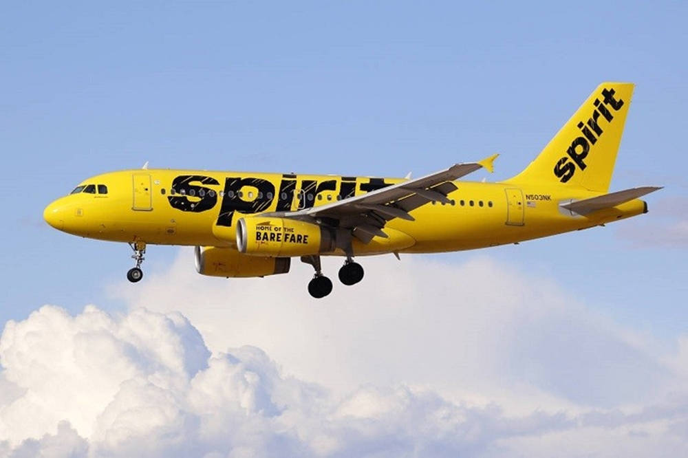 飛機 桌布 壁紙 — 一架亮黃色的Spirit Airlines噴射機放下起落架，在藍天白雲中翱翔。