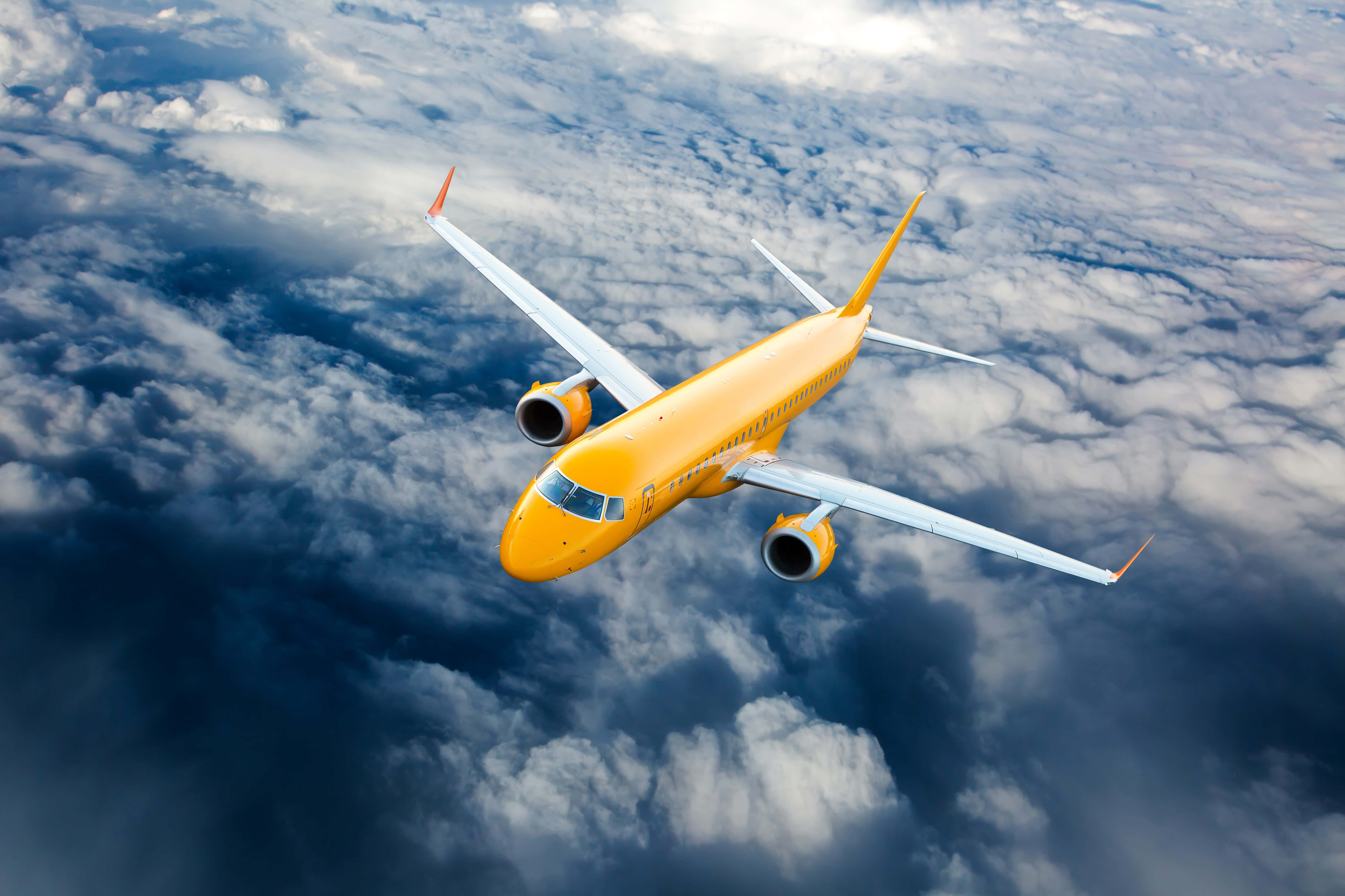 Plane 桌布 壁紙 — 一架亮黃色的客機在深藍色天空下，翱翔於大片蓬鬆白雲之上。