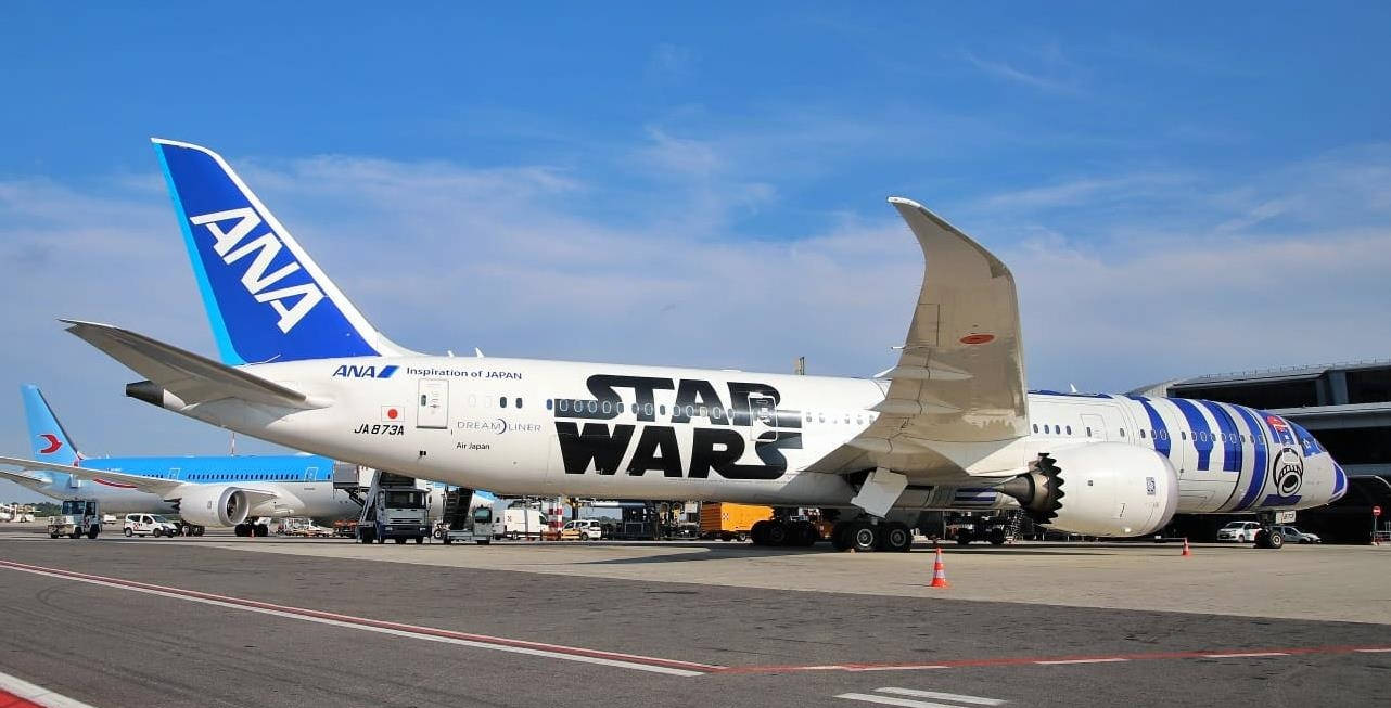 飛機 桌布 壁紙 — 一架以星際大戰為主題的ANA波音787夢幻客機停泊在機場停機坪上，天空清澈湛藍。