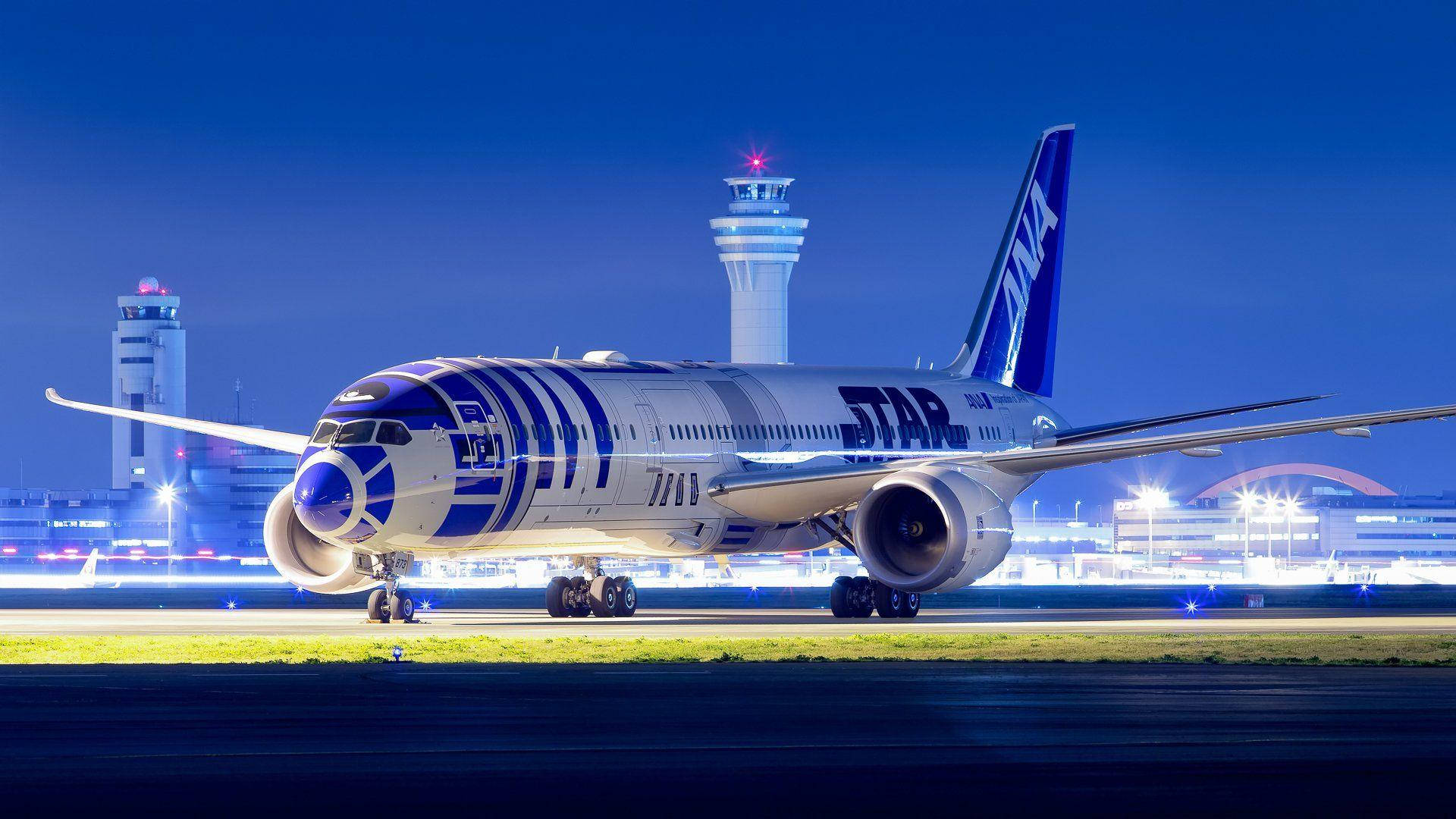 Airport 桌布 壁紙 — 一架以星際大戰為主題的ANA飛機，帶有R2-D2塗裝，在深藍色夜空下，機場燈光閃爍的跑道上滑行。