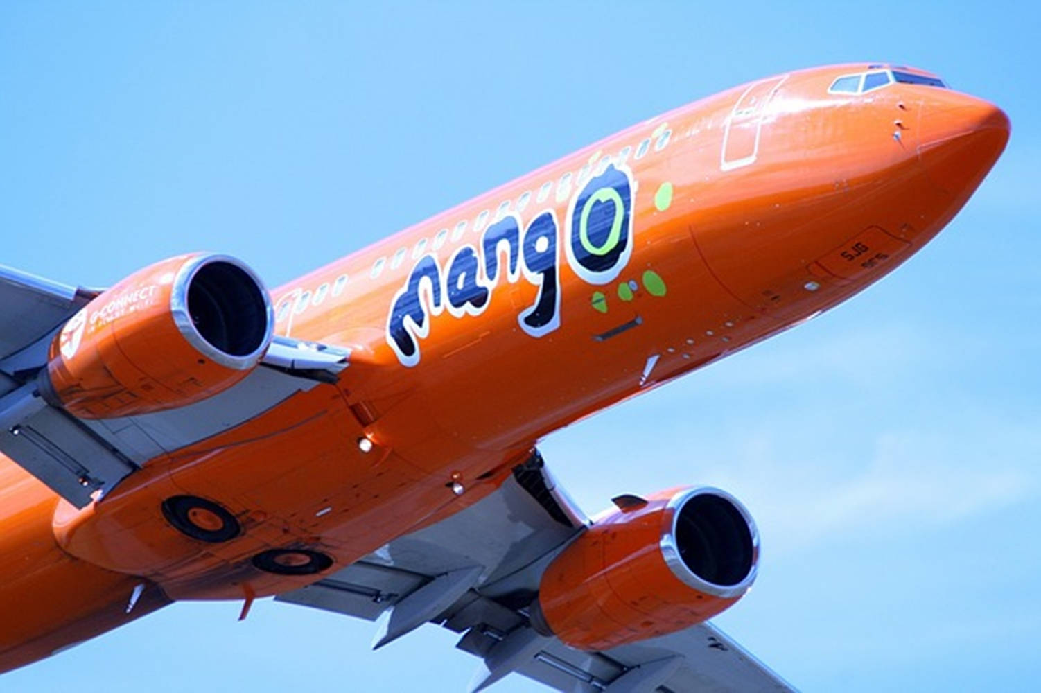 雲朵 桌布 壁紙 — 一架充滿活力的橘色Mango Airlines噴射機在清澈的藍天中翱翔，其獨特的標誌清晰可見。