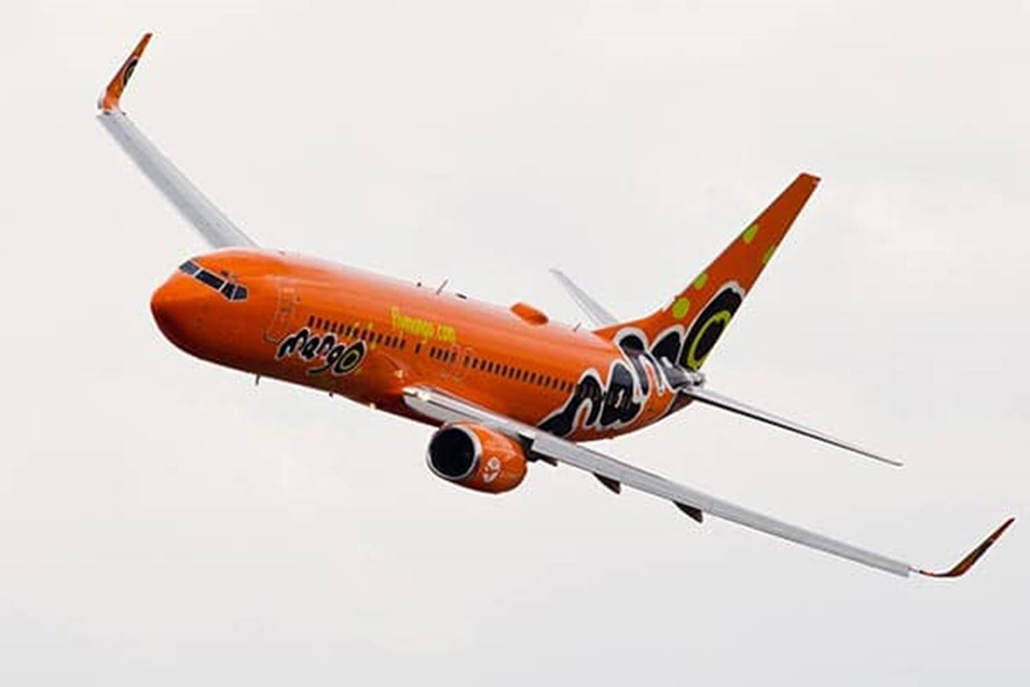 飛機 桌布 壁紙 — 一架充滿活力的橙色Mango Airlines噴射機在蒼白的陰天中翱翔，帶有醒目的黑色和綠色品牌標識。
