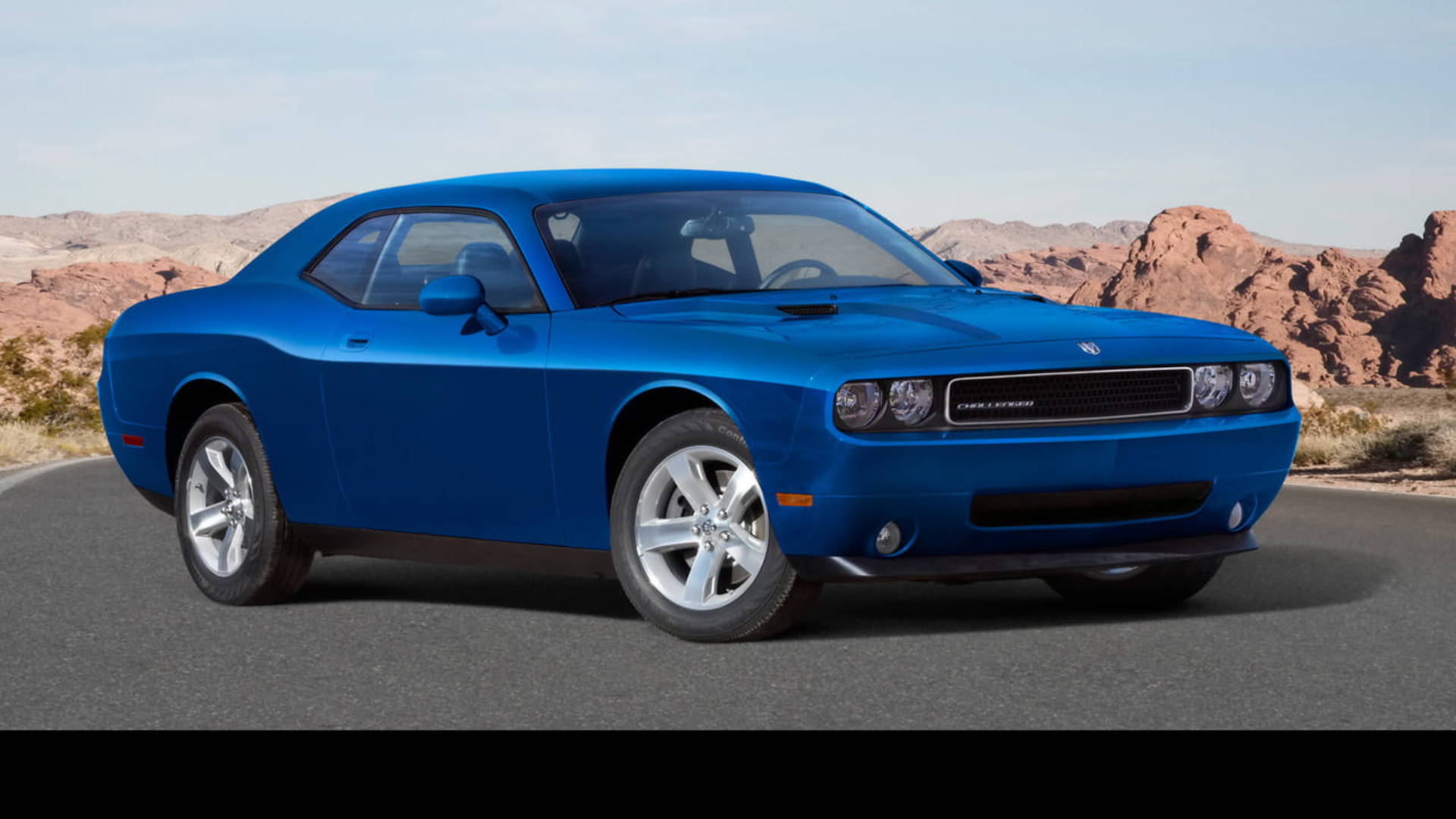  壁紙 — 一架充滿活力的藍色 Dodge Challenger 肌肉車停泊在沙漠公路上，背景是紅色岩石地貌。