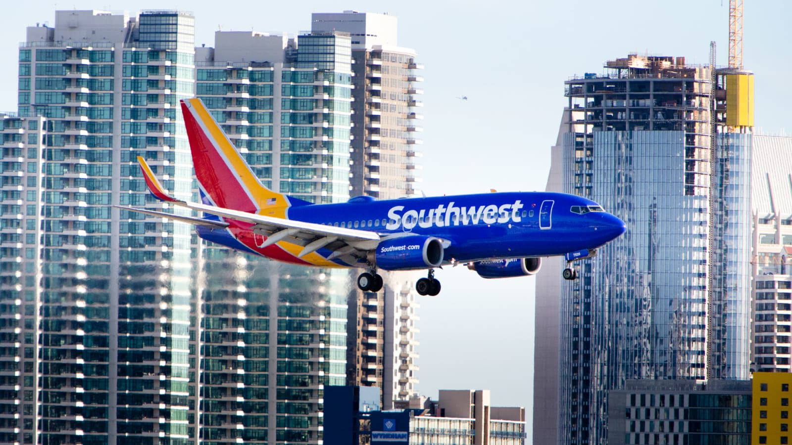 Plane 桌布 壁紙 — 一架充滿活力的西南航空飛機在晴朗的天空下攀升，經過高聳的玻璃摩天大樓。