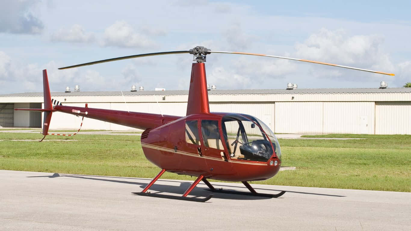 1366x768 Helicopters 桌布 壁紙 — 一架光澤的紅色直升機停在停機坪上，旁邊是草地，天空部分多雲。