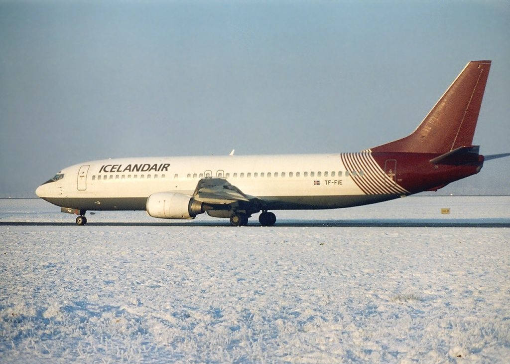 飛機 桌布 壁紙 — 一架冰島航空波音737停放在白雪覆蓋的跑道上，天空呈現淡藍色。