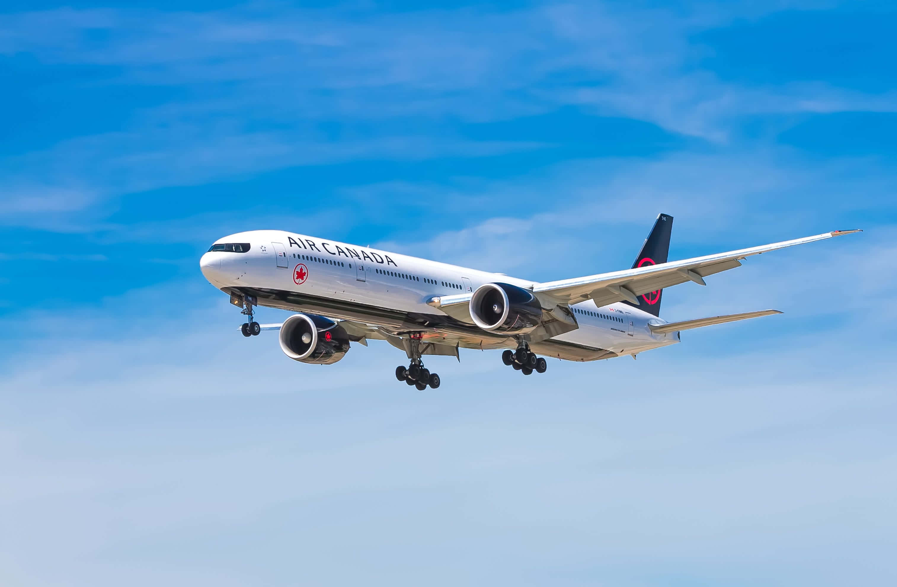 飛機 桌布 壁紙 — 一架加拿大航空的飛機放下起落架，在晴朗藍天和薄雲中翱翔。