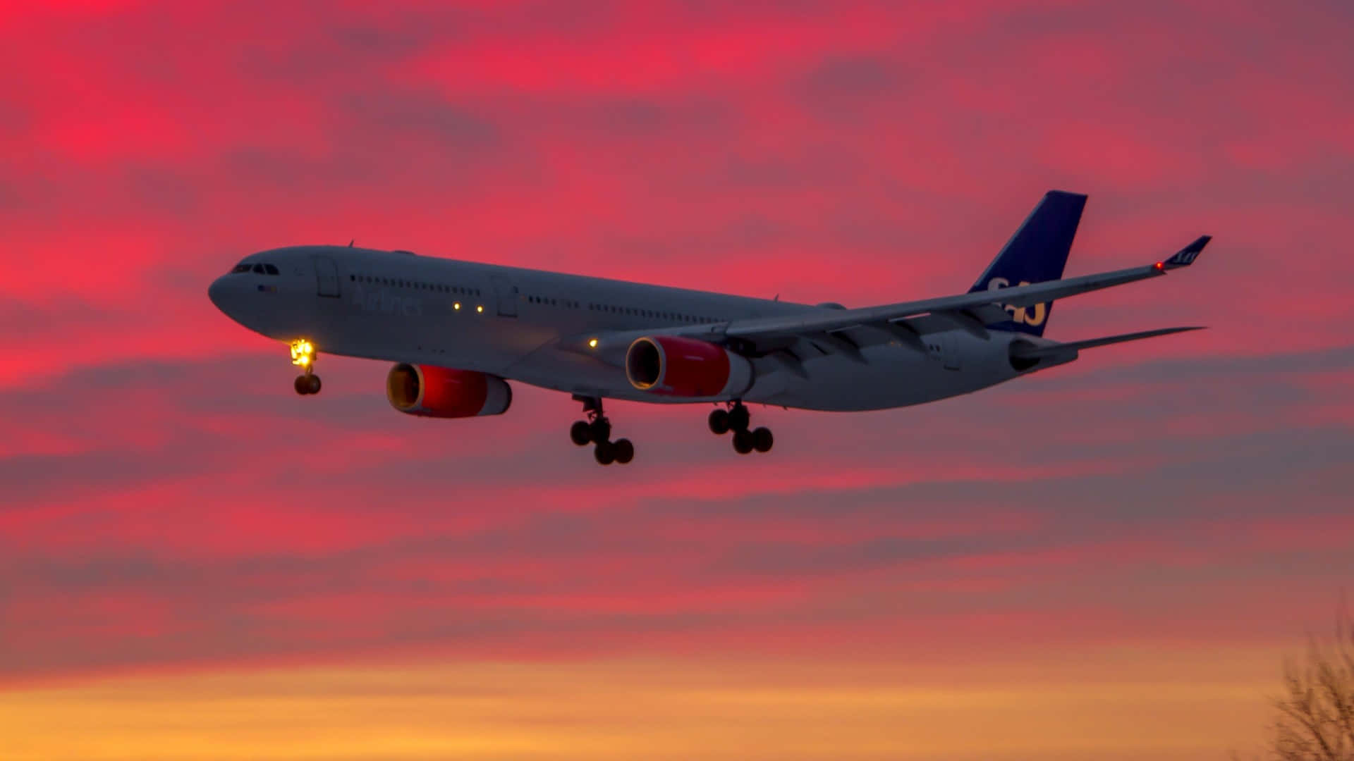 HD Plane 桌布 壁紙 — 一架北歐航空的空中巴士A330在熾熱的日落天空下下降，引擎發光，起落架已放下。