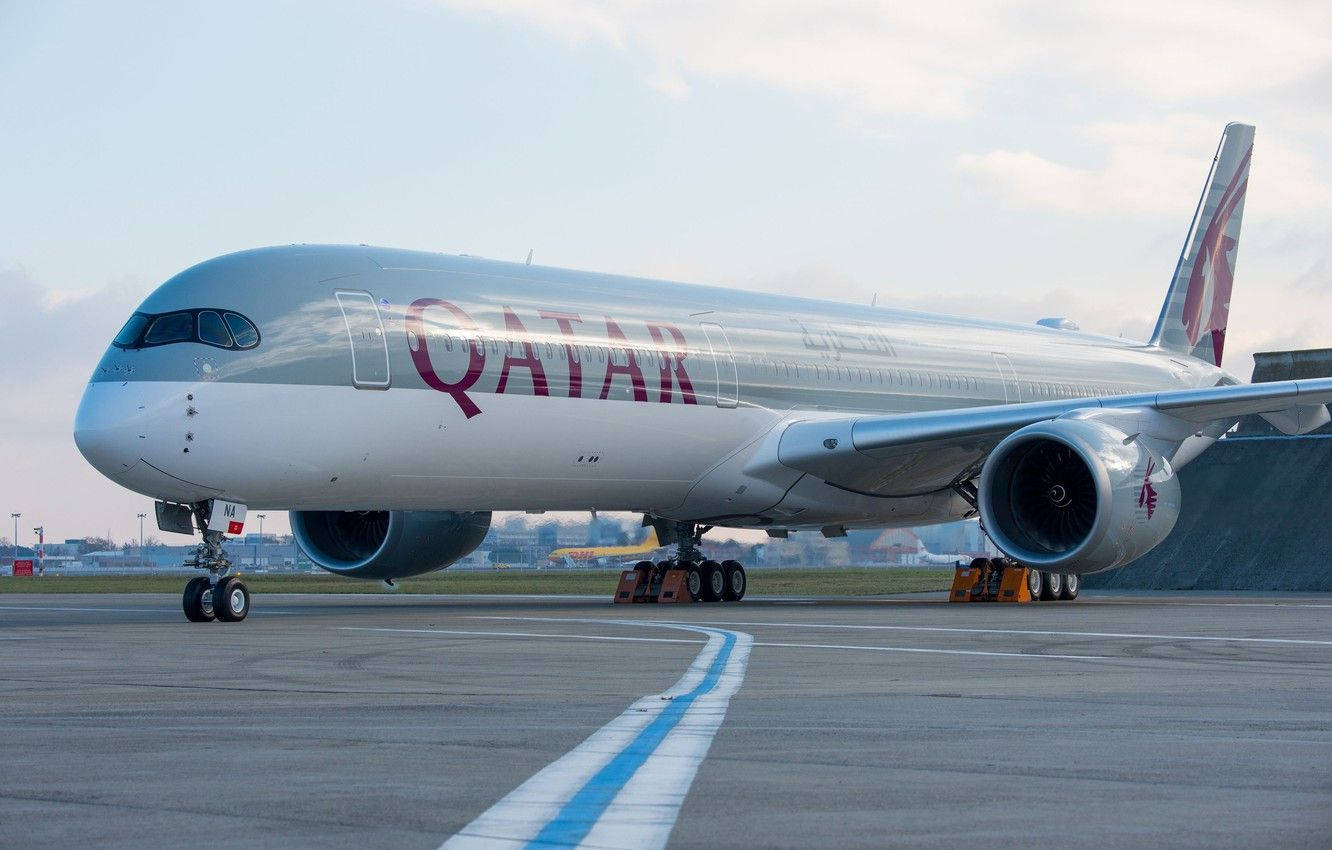 雲朵 桌布 壁紙 — 一架卡達航空的空中巴士A350在柔和日光下於機場停機坪閃耀，藍色跑道線引導其路徑。