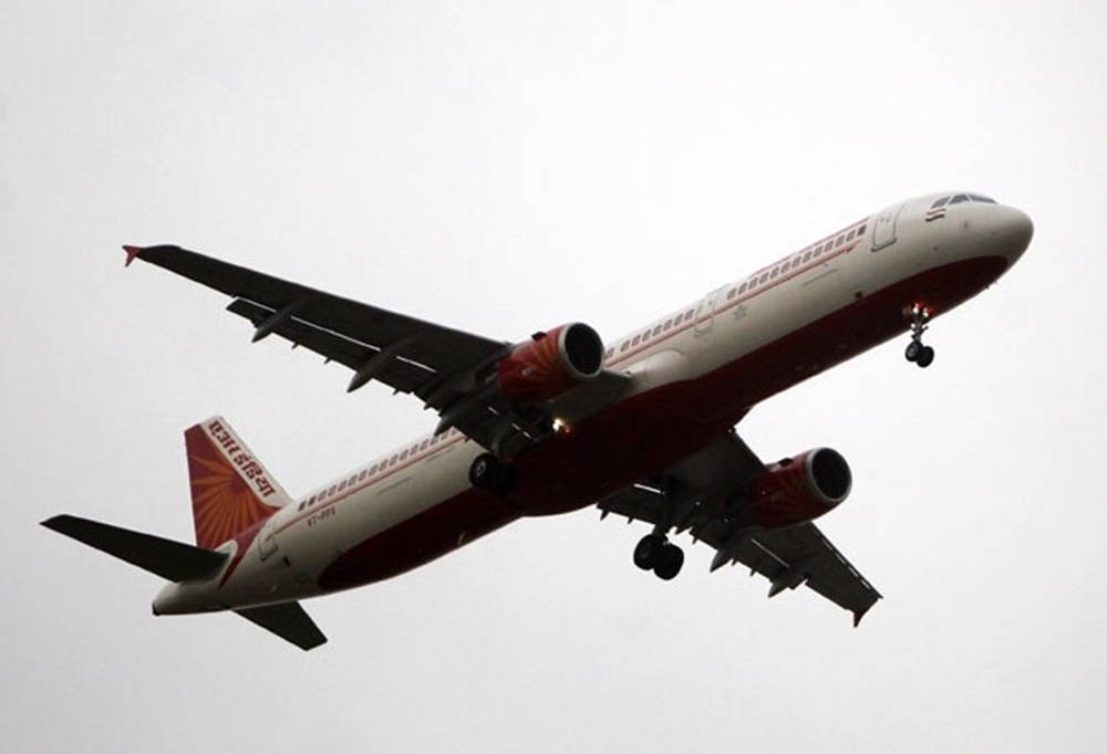 飛機 桌布 壁紙 — 一架印度航空的空中巴士A320以紅白塗裝，在蒼白多雲的天空中上升，起落架已放下。