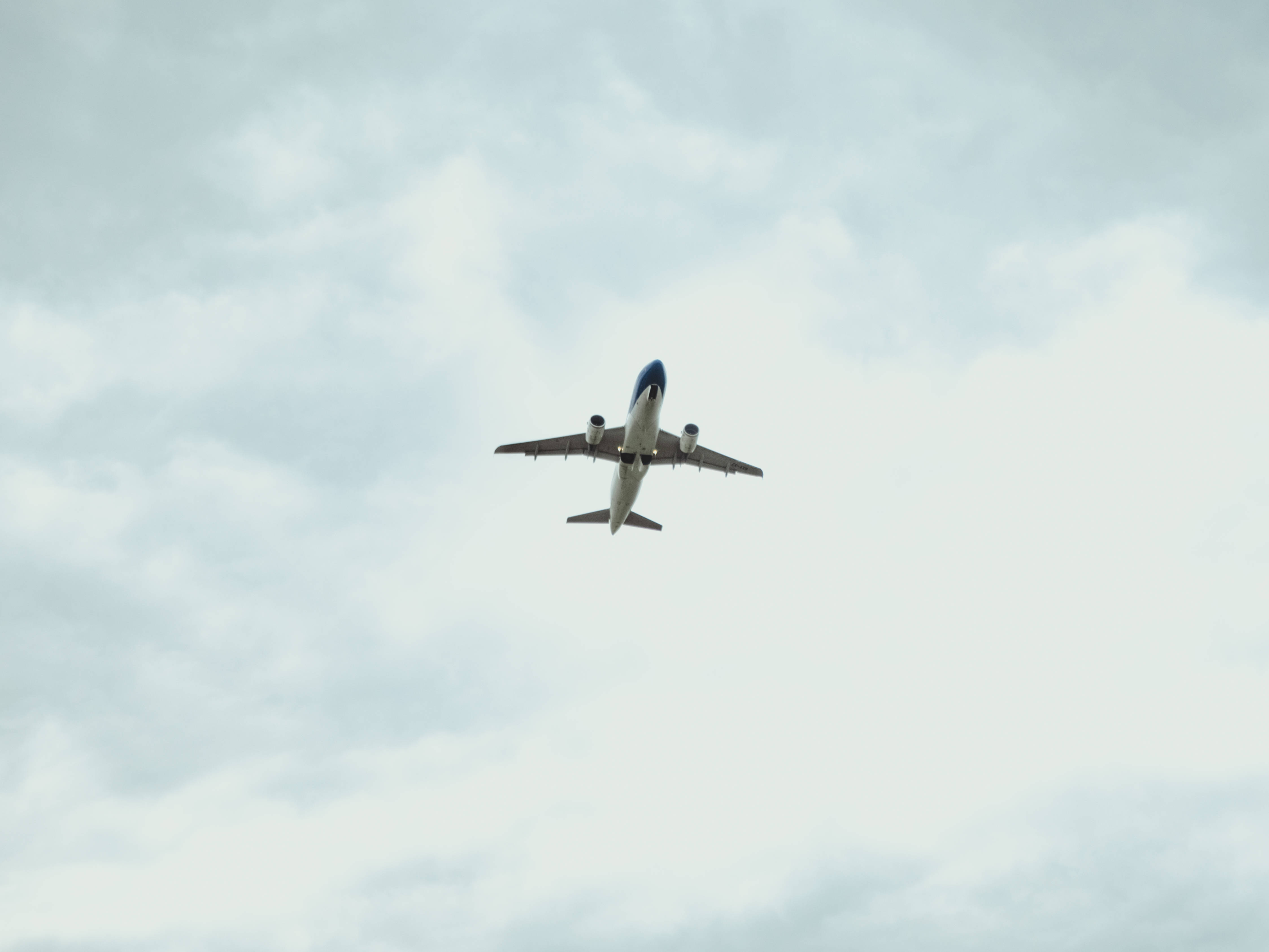 Aerospace 桌布 壁紙 — 一架商用飛機在下方仰望柔和灰色多雲的天空中翱翔。