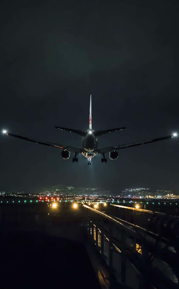 Flight 桌布 壁紙 — 一架商用飛機在夜間下降，跑道燈光在機翼下閃爍，映襯著黑暗的天空。