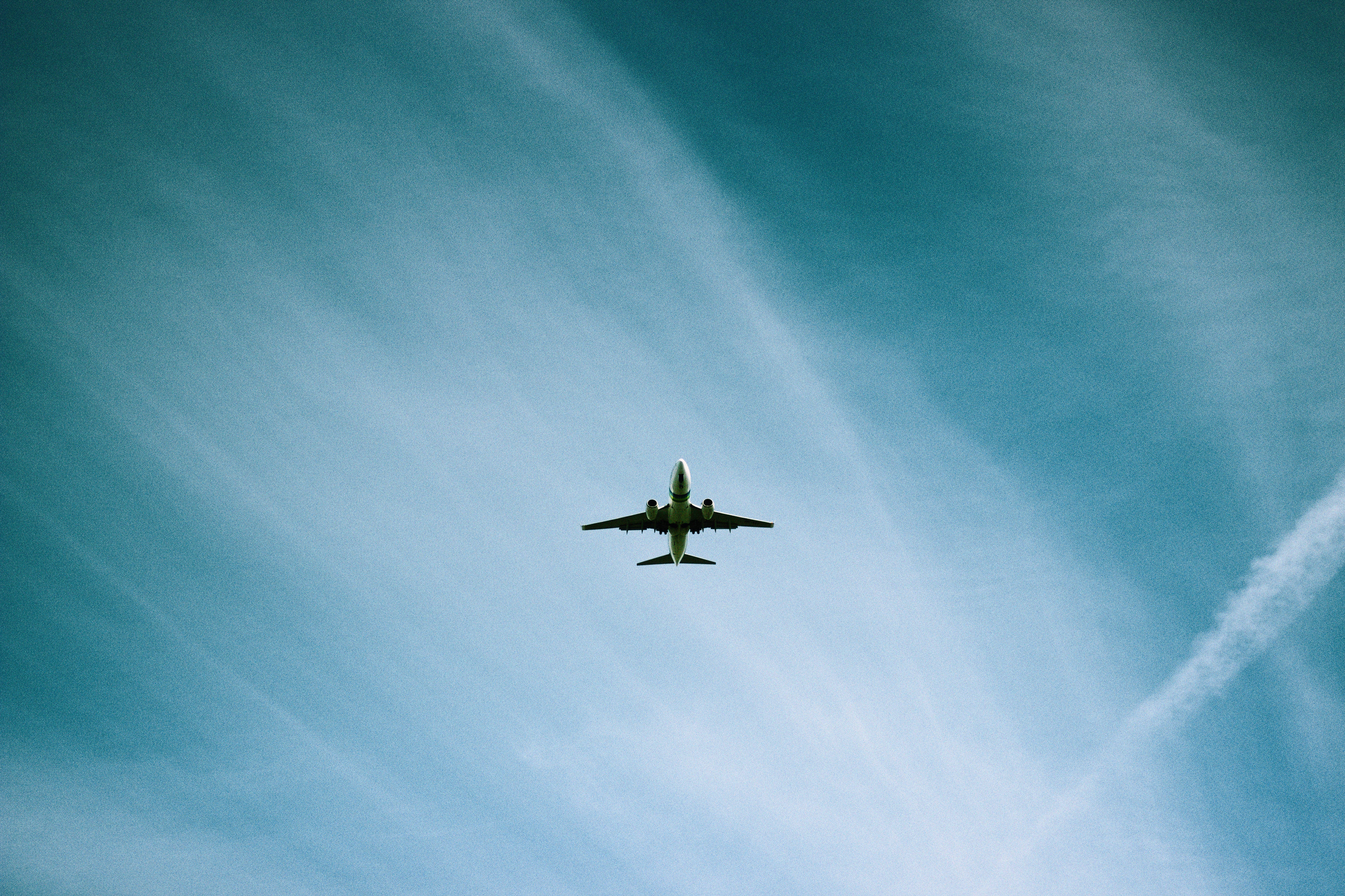飛機 桌布 壁紙 — 一架商用飛機在廣闊的藍天中翱翔，天空點綴著縷縷白雲。