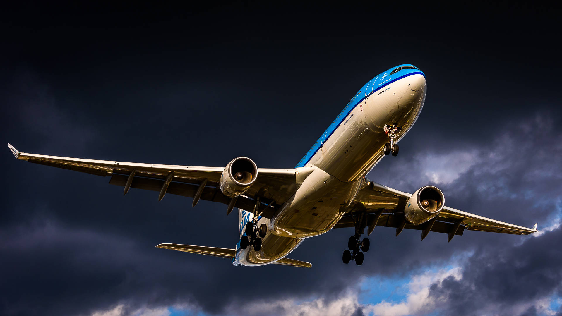 飛機 桌布 壁紙 — 一架商用飛機在戲劇性的黑暗暴風雨天空中強力攀升，藍天隱約透出。