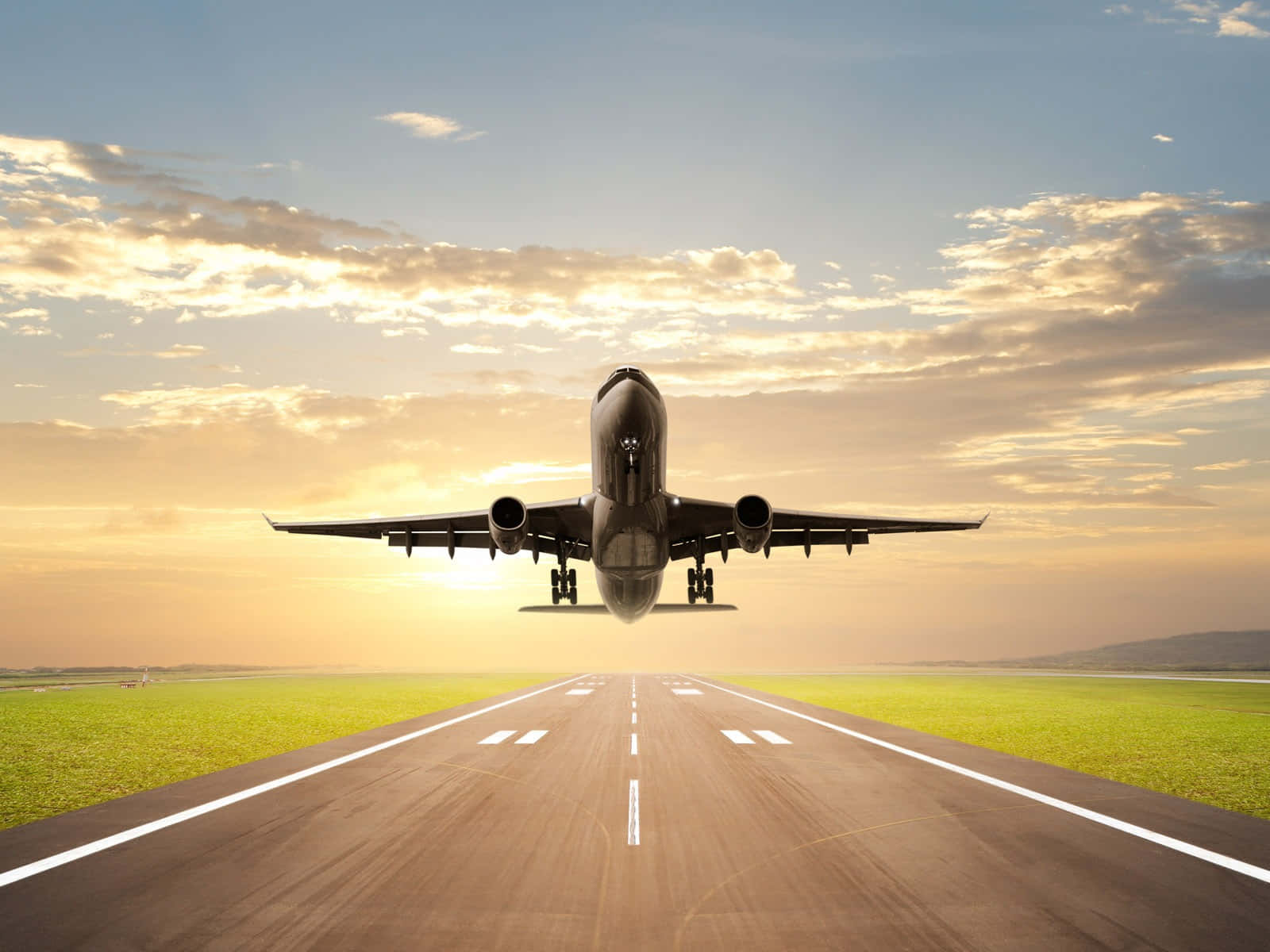 Aviation 桌布 壁紙 — 一架商用飛機在日落時從跑道起飛，背景是金色的雲朵和綠色的田野。