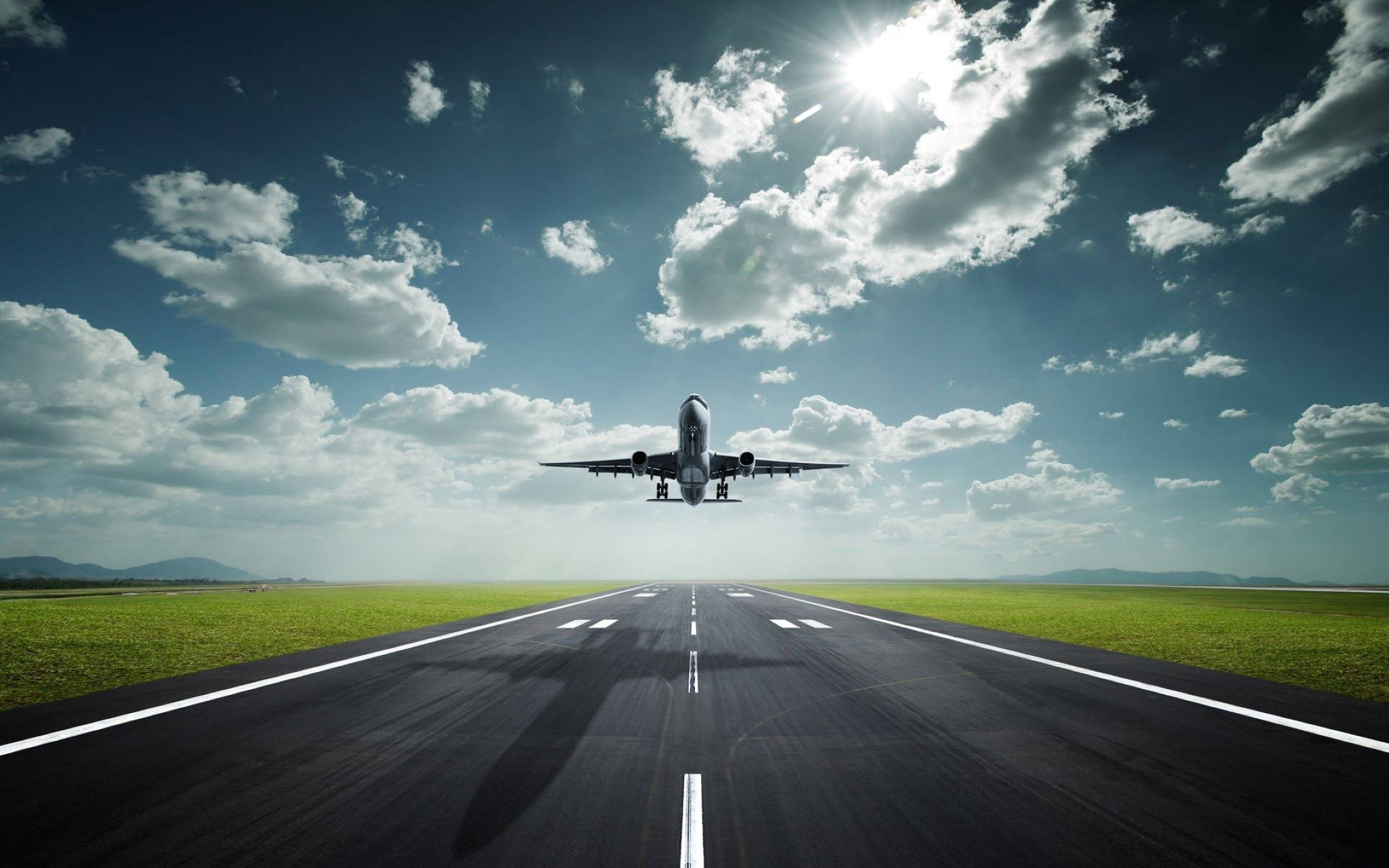 Runway 桌布 壁紙 — 一架商用飛機在明亮的陽光和散落的雲朵下從跑道上升起。