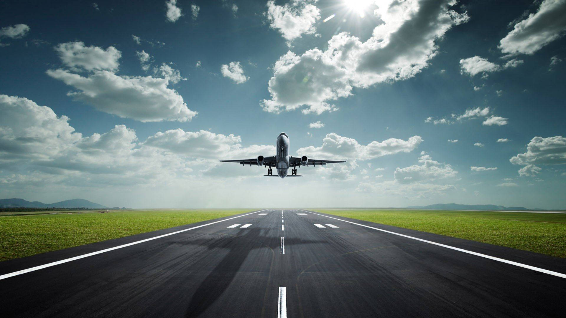 Runway 桌布 壁紙 — 一架商用飛機在明亮的陽光和散落的雲朵下從跑道上升起。