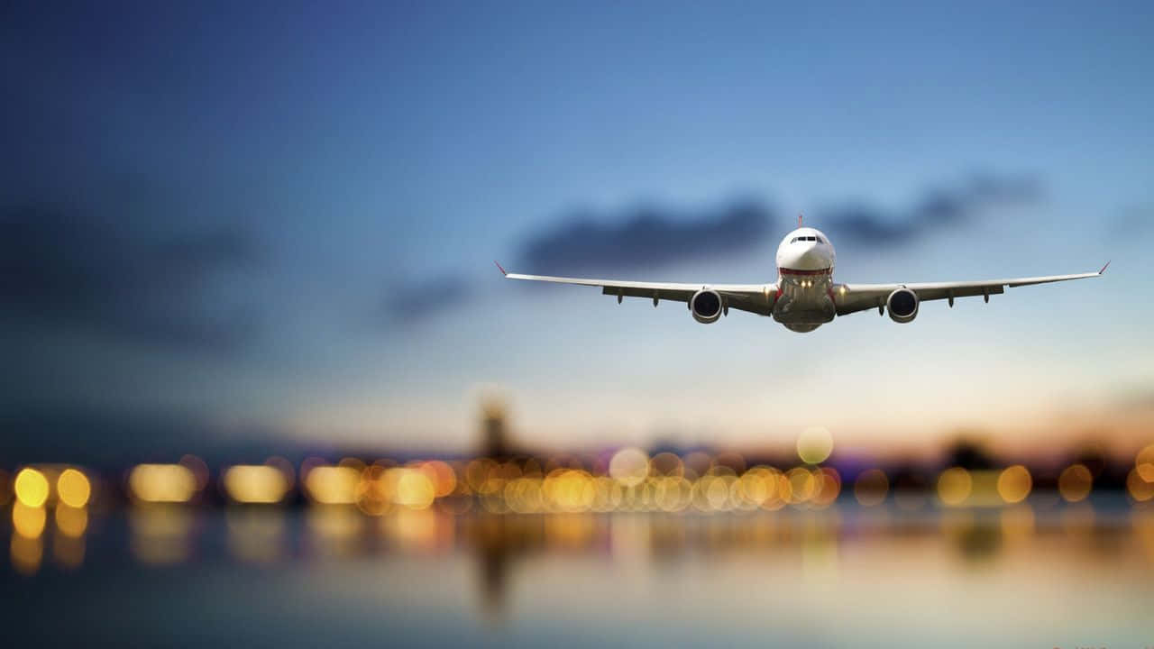 720p Plane 桌布 壁紙 — 一架商用飛機在暮色天空中攀升，下方水面倒映著模糊的城市燈光。