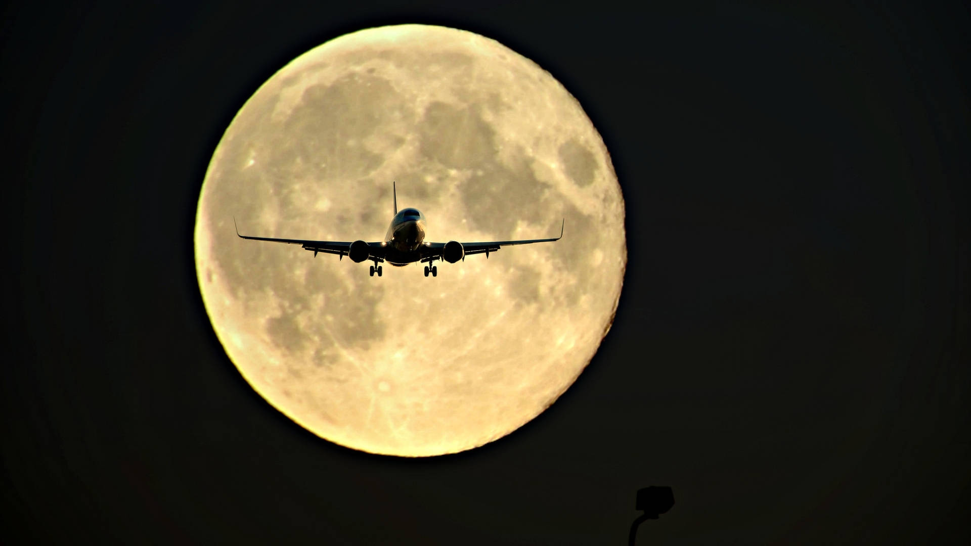 HD Plane 桌布 壁紙 — 一架商用飛機在漆黑的夜空中，以巨大明亮的滿月為背景呈現剪影。
