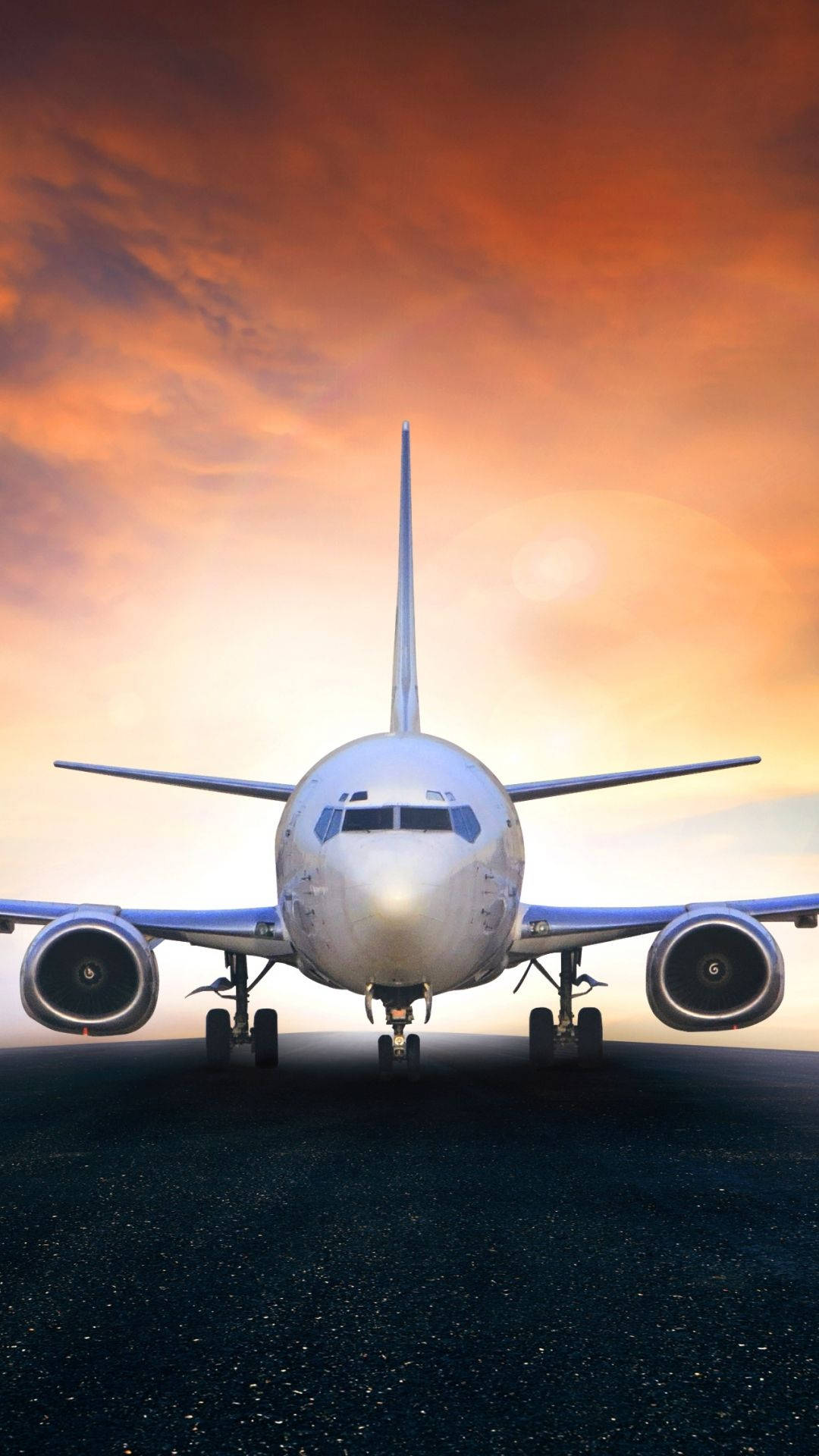 Runway 桌布 壁紙 — 一架商用飛機在火紅橙色的日落天空下，於跑道上朝向前方。
