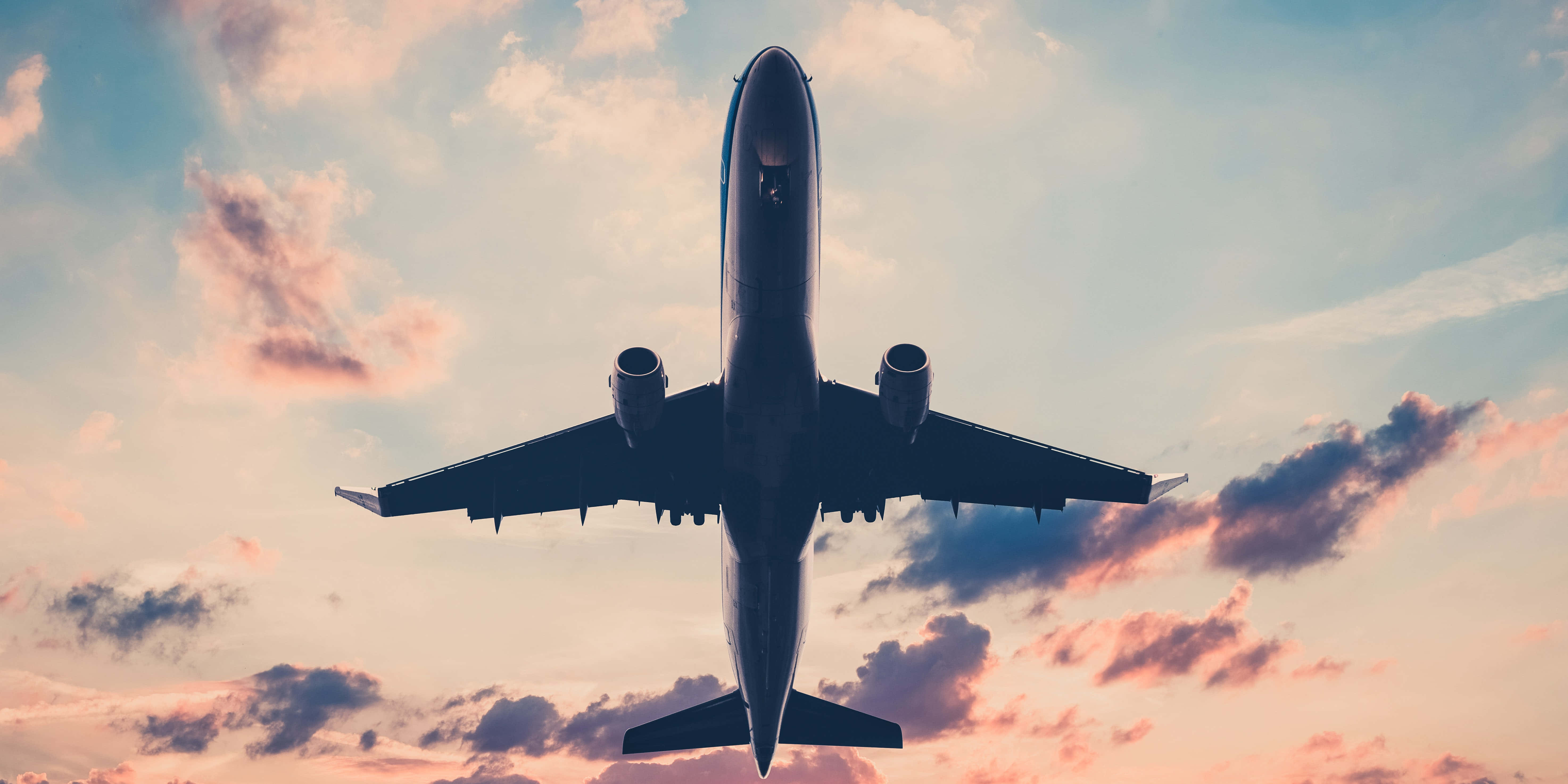 Plane 桌布 壁紙 — 一架商用飛機在色彩繽紛的日落天空翱翔，天空被粉紅色和橙色的雲彩渲染。