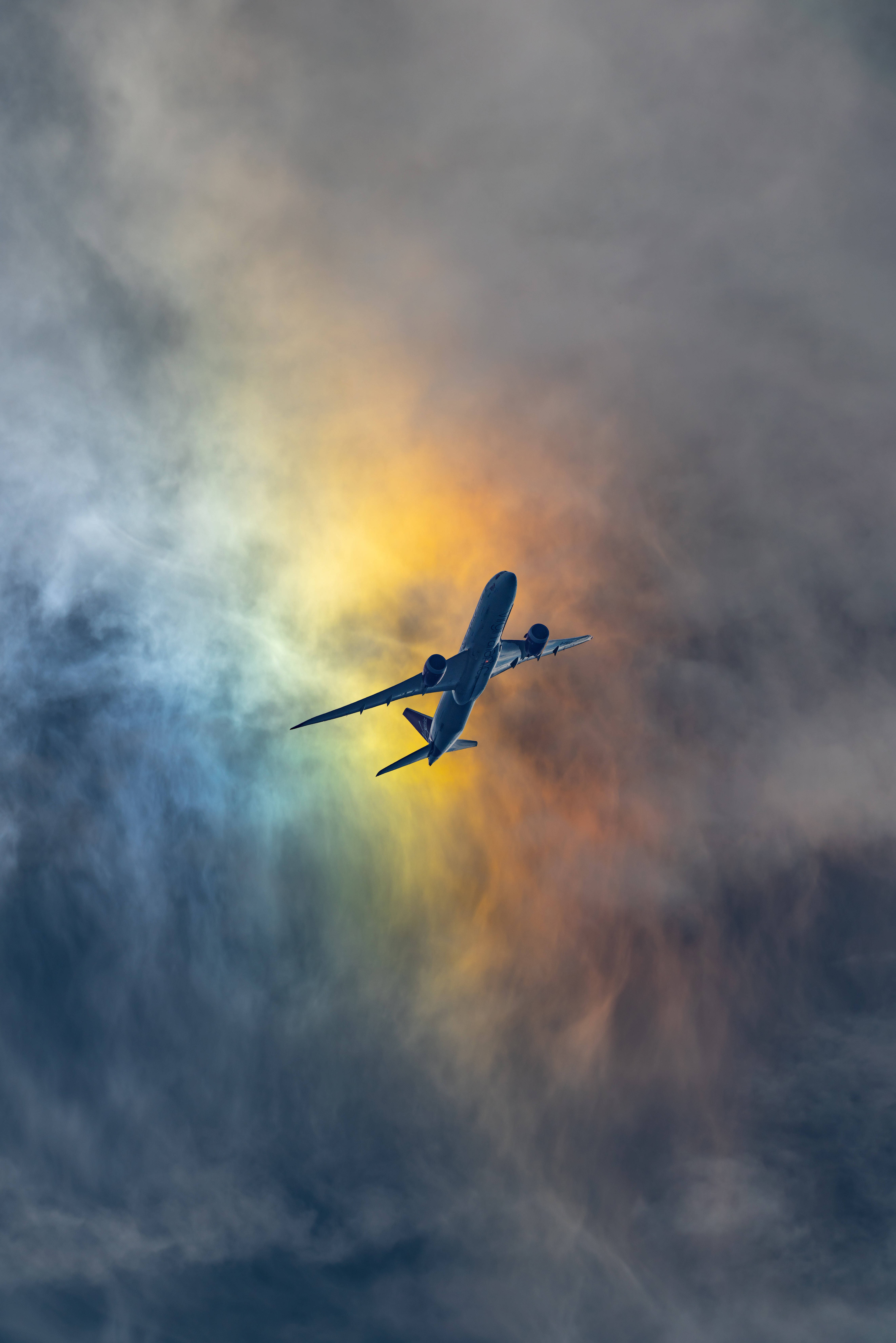 飛機 桌布 壁紙 — 一架商用飛機在金色夕陽餘暉照耀的戲劇性雲層中翱翔。