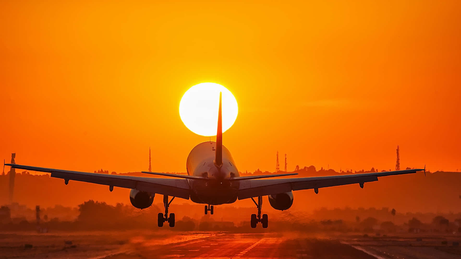 HD Plane 桌布 壁紙 — 一架商用飛機在降落跑道時，以熾熱的橙色夕陽為背景形成剪影。