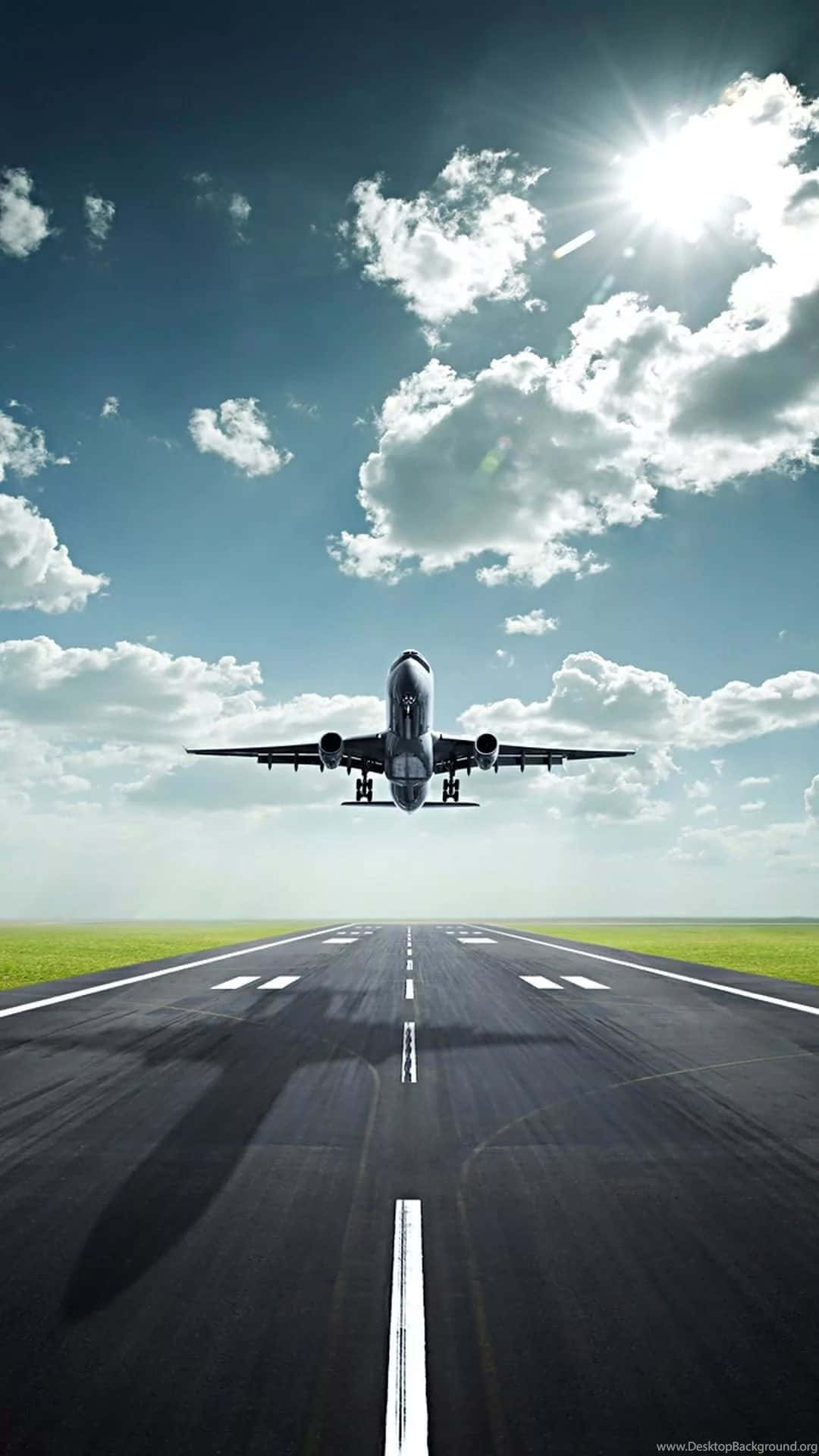 桌布 壁紙 — 一架商用飛機在陽光普照、雲朵散佈的天空下從跑道上升起。