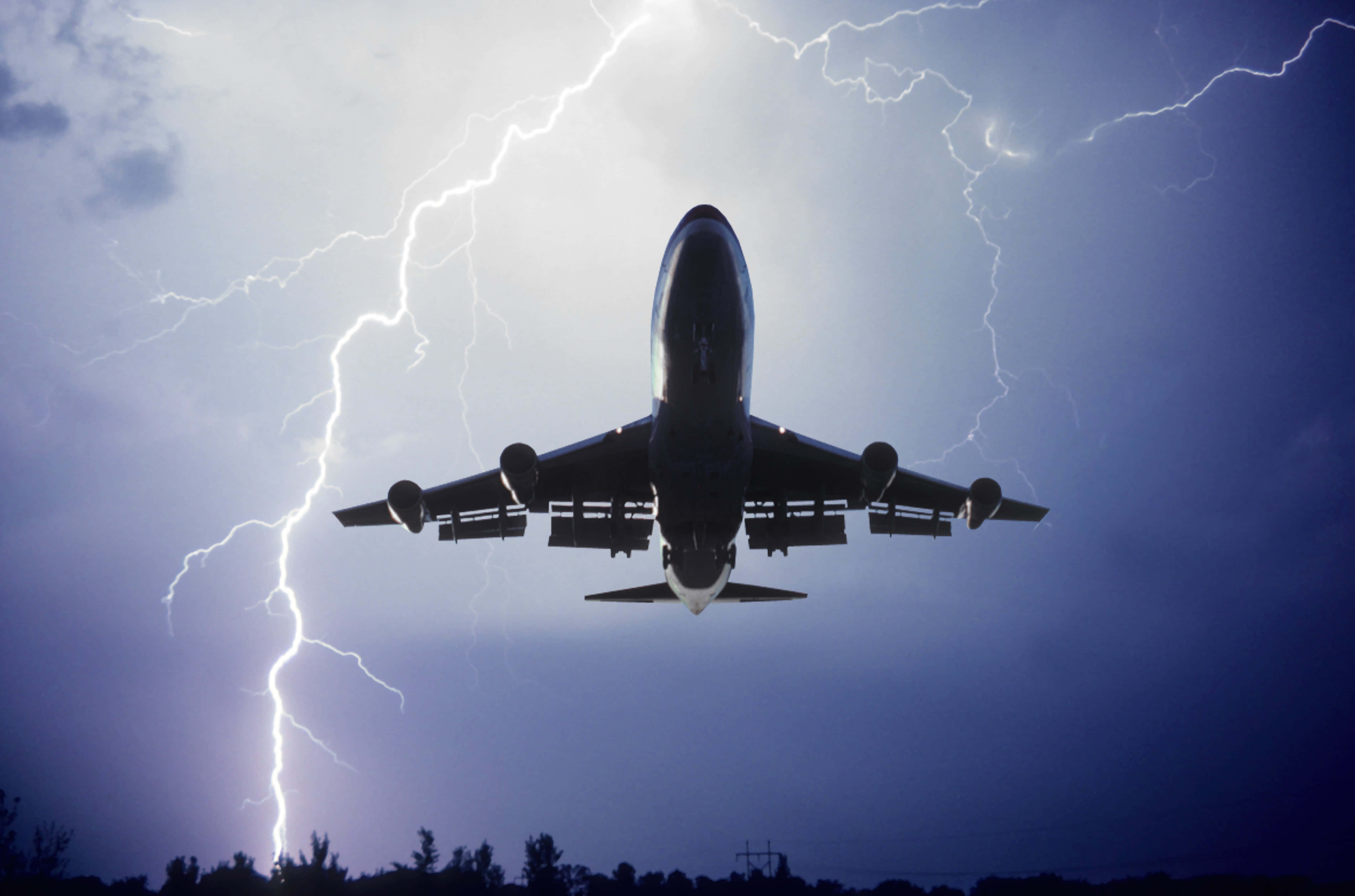 飛機 桌布 壁紙 — 一架商用飛機在頭頂飛過，明亮的閃電在暴風雨的暮色天空中分叉。