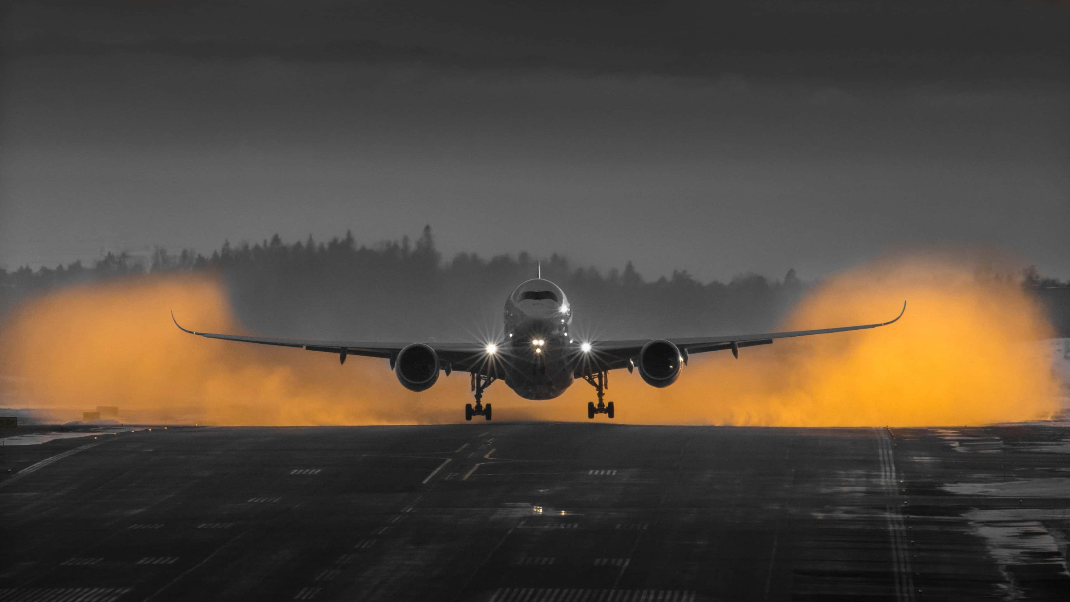 Plane 桌布 壁紙 — 一架商用飛機在黃昏時降落在潮濕的跑道上，橙色的引擎排氣在黑暗的天空中發光。
