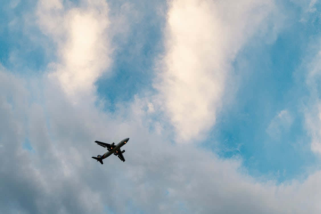 Plane 桌布 壁紙 — 一架商用飛機在點綴著蓬鬆白雲的鮮豔藍天中翱翔。