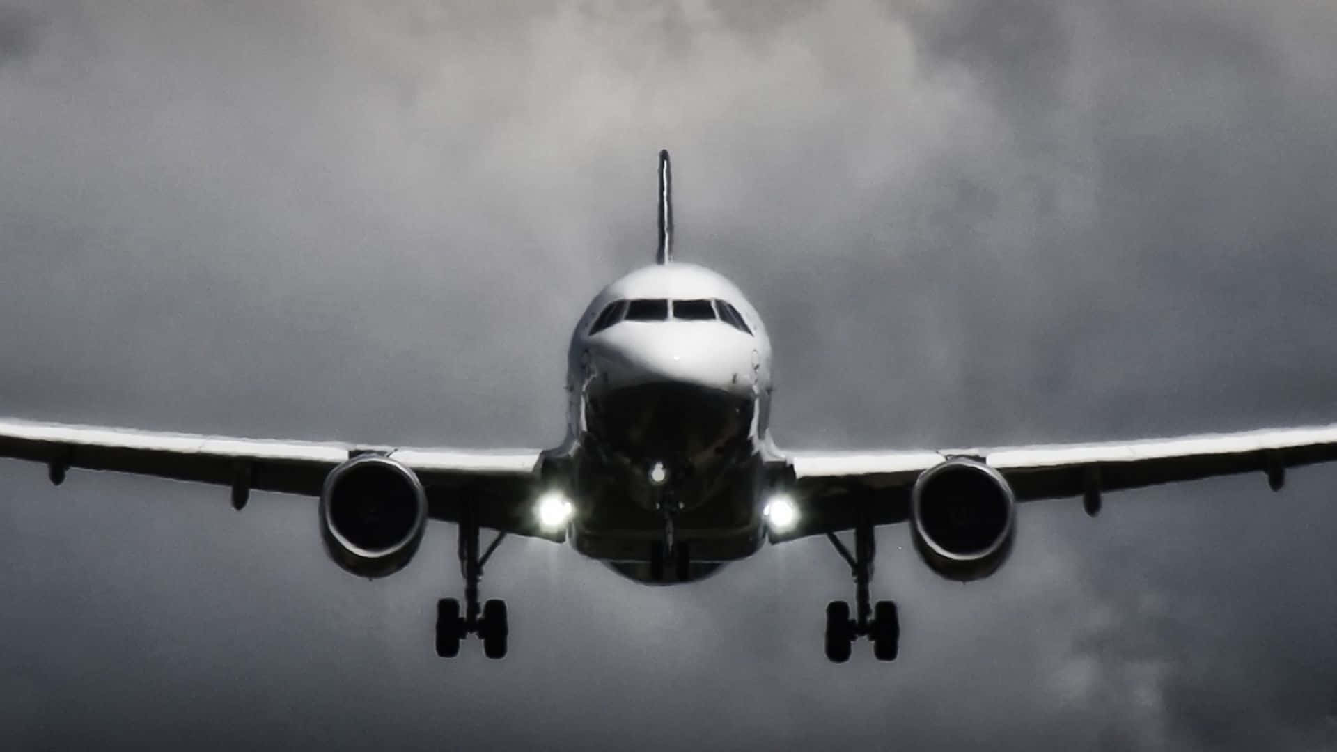 一架飛機在暴風雨的天空下亮著燈接近著陸。 — 飛機 壁紙