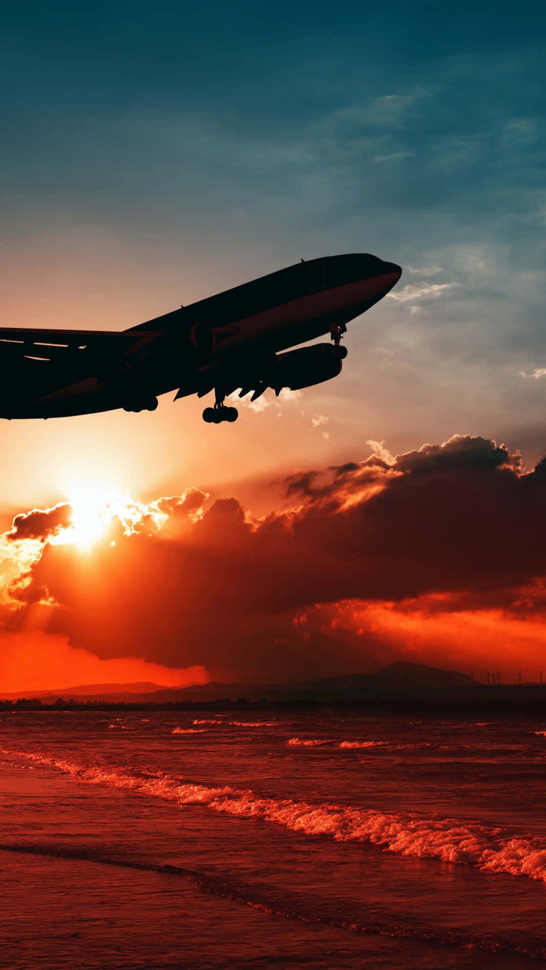 Plane 桌布 壁紙 — 一架噴射機在戲劇性的雲層下，於發光的海洋上以熾熱的日落為背景形成剪影。