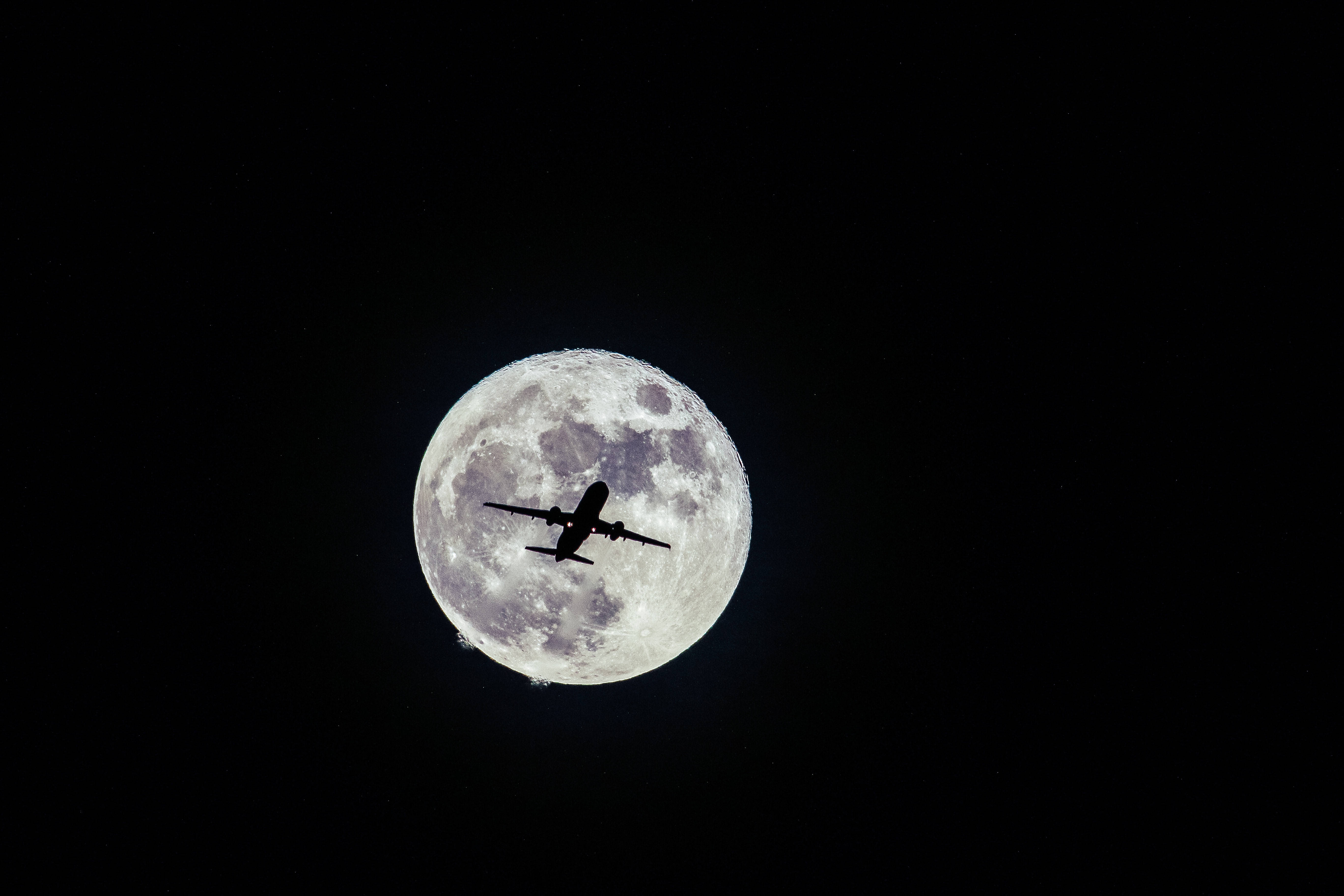 飛機 桌布 壁紙 — 一架噴射飛機在無星的夜空中，以巨大而詳細的滿月為背景的剪影。