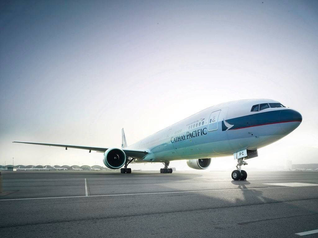 Airport 桌布 壁紙 — 一架國泰航空波音777停放在機場停機坪上，天空朦朧，晨光柔和。